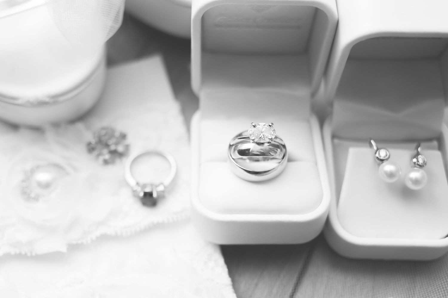 Wedding rings and jewelry boxes arranged on white surface in monochrome style.