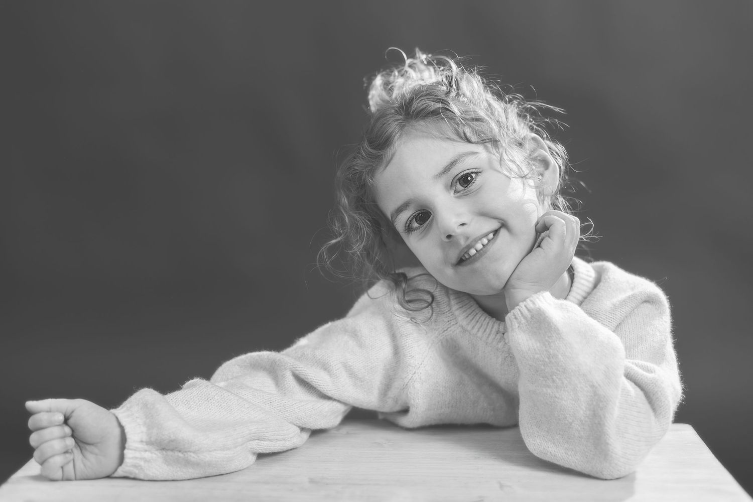 A series of black and white photos showing a young child in playful poses while lying down.