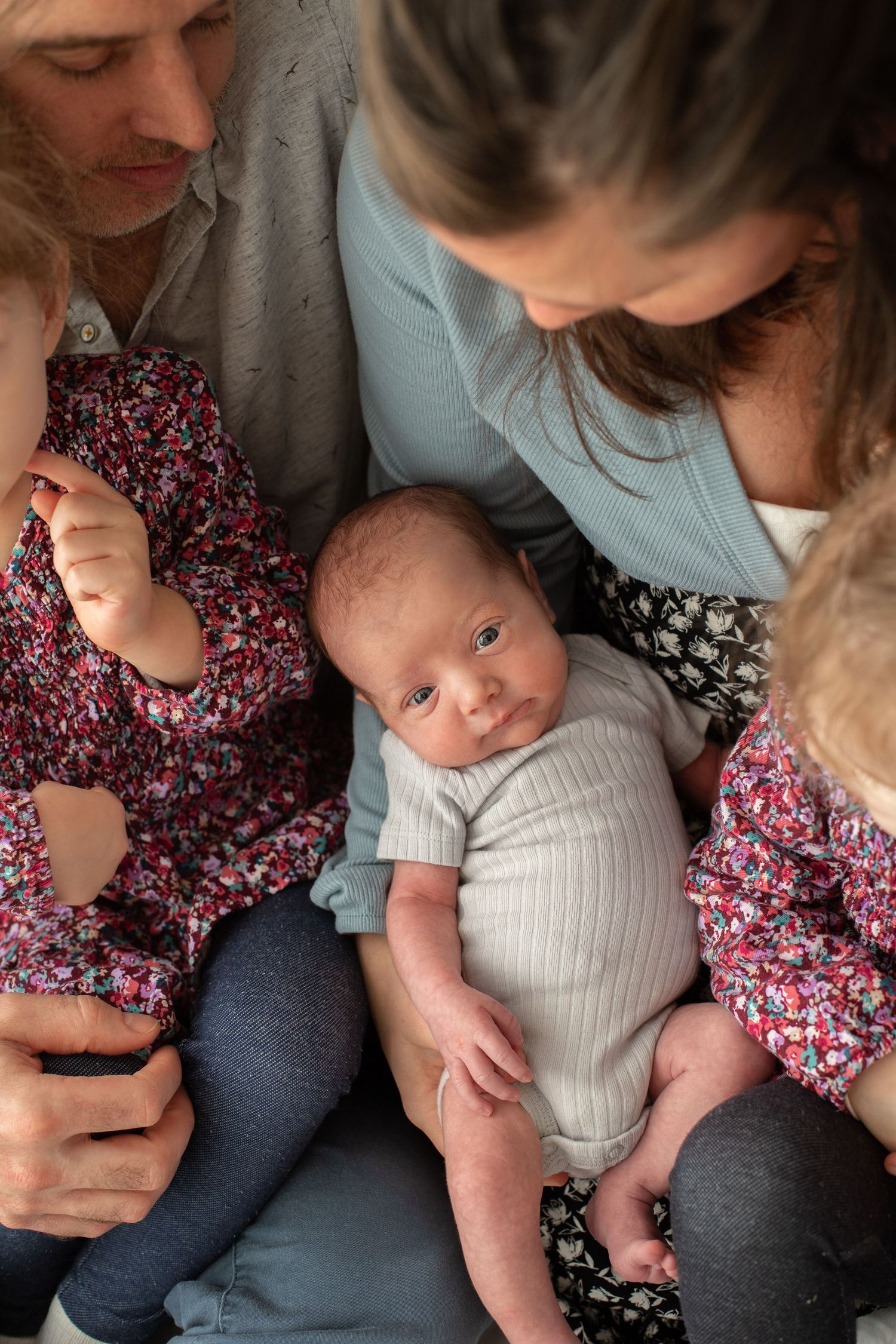 A series of intimate moments showing gentle interaction with a small infant wearing a white onesie.