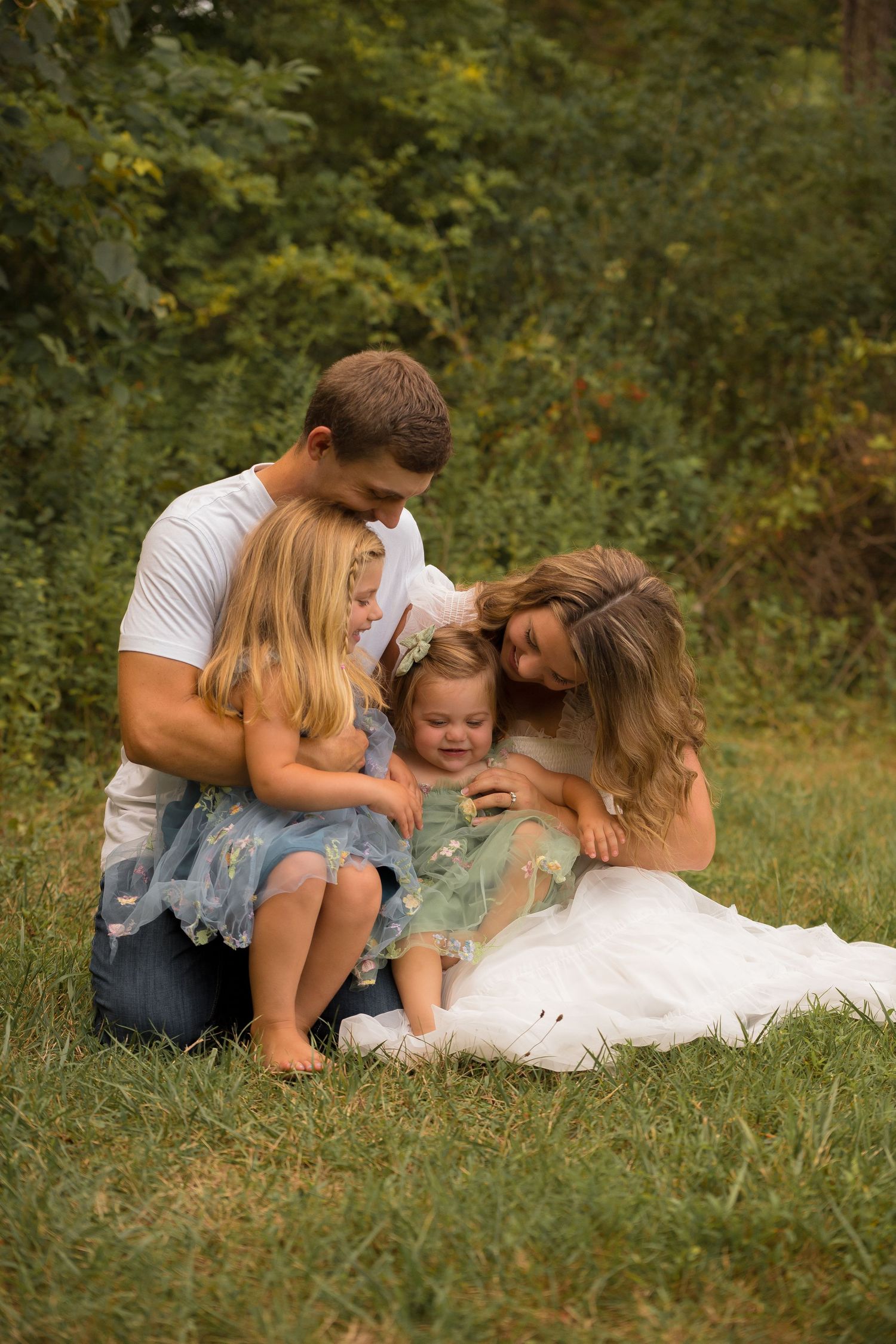 Family laying together in grass during outdoor photo session in natural setting.