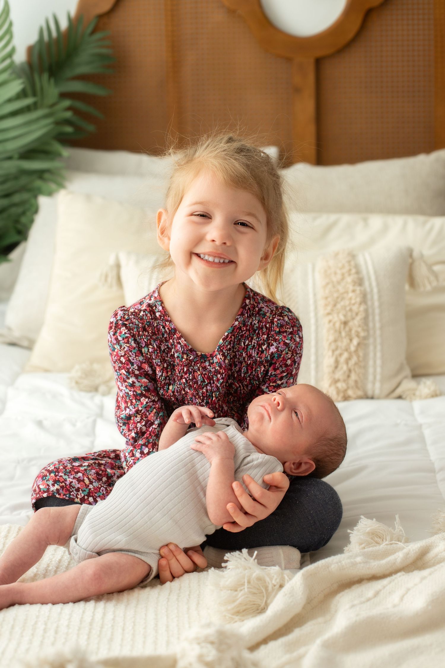 Sweet sibling moment on white bedding with decorative pillows.