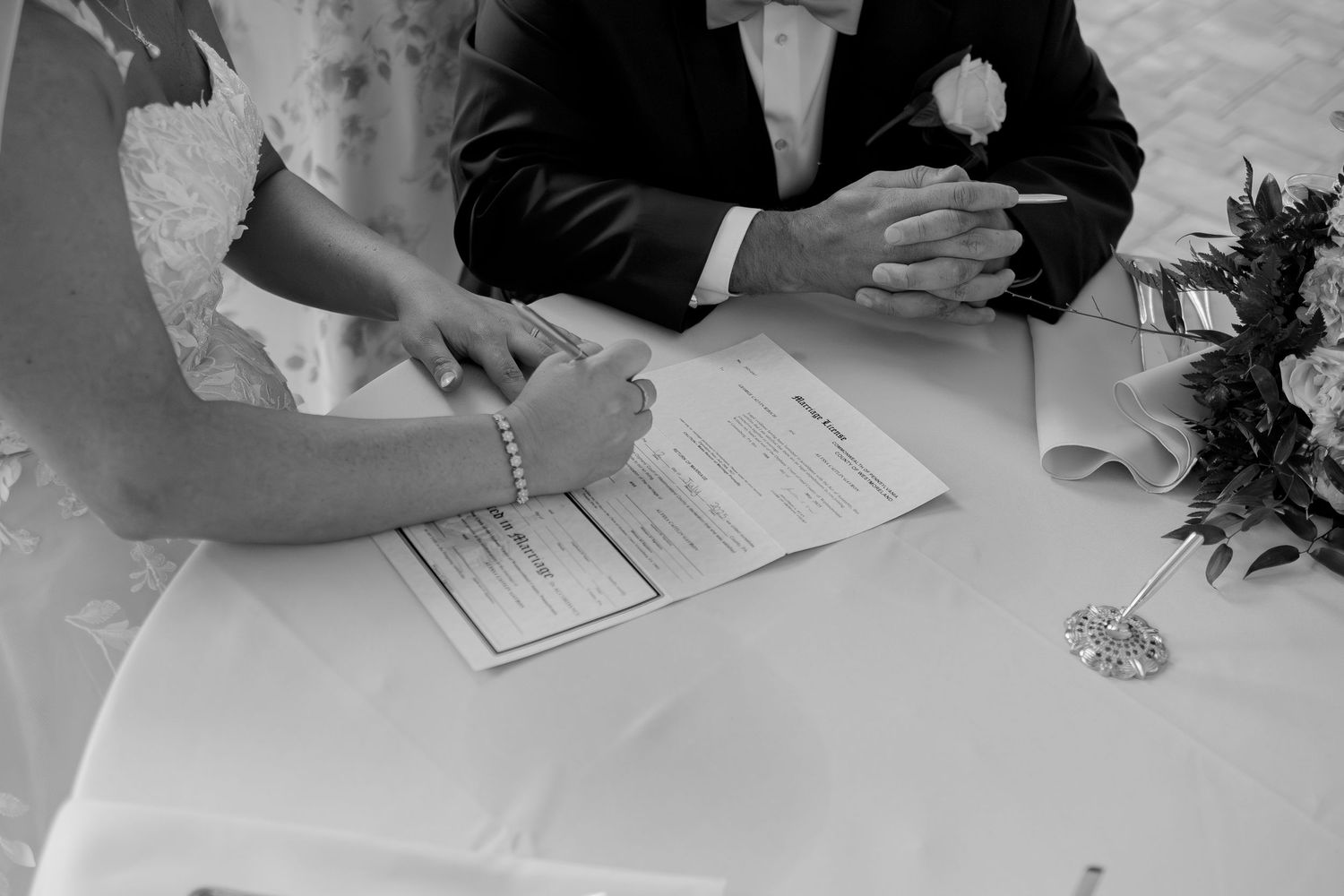 Wedding couple signing marriage documents at ceremony.