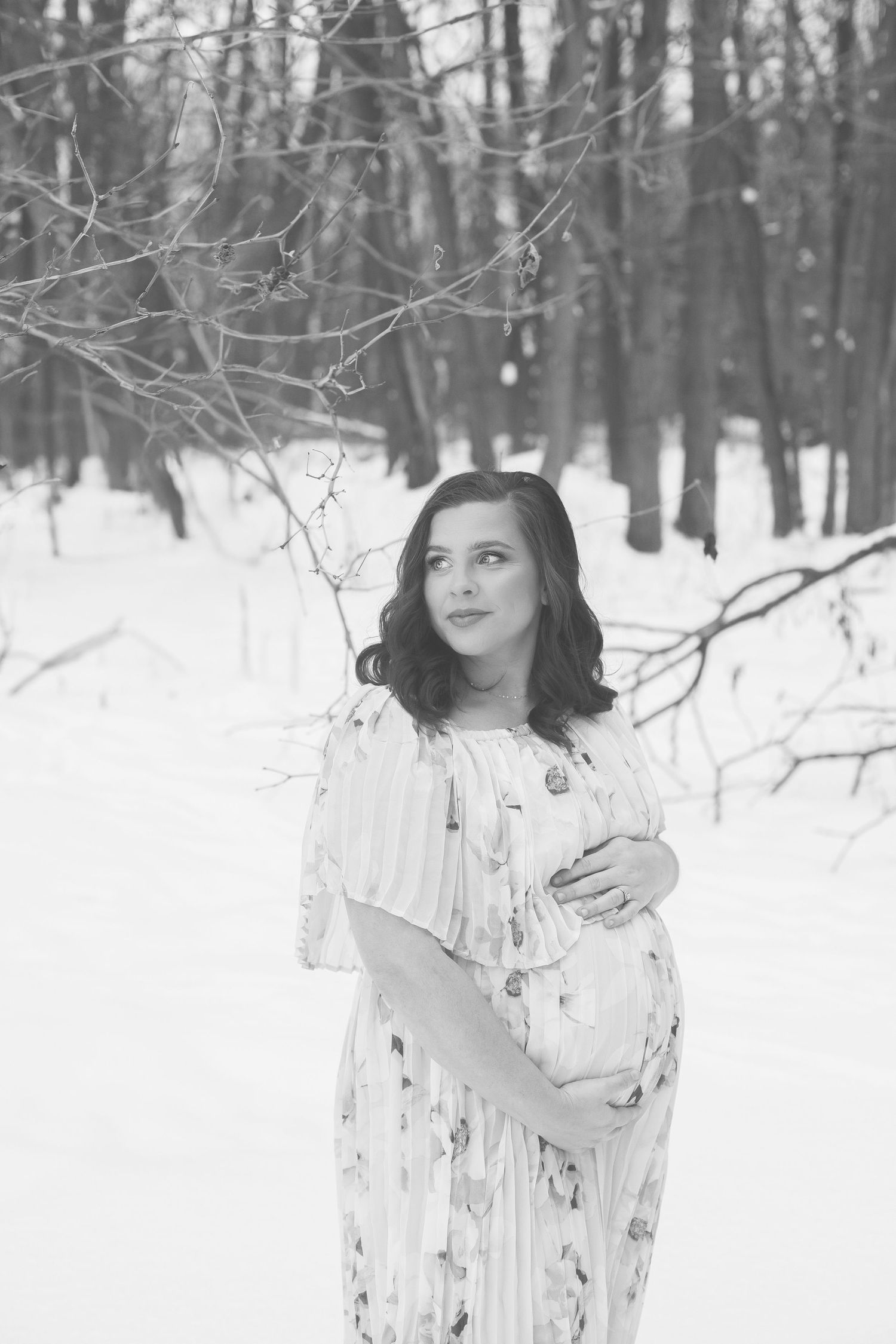 Ethereal winter maternity portraits in snow covered forest setting.