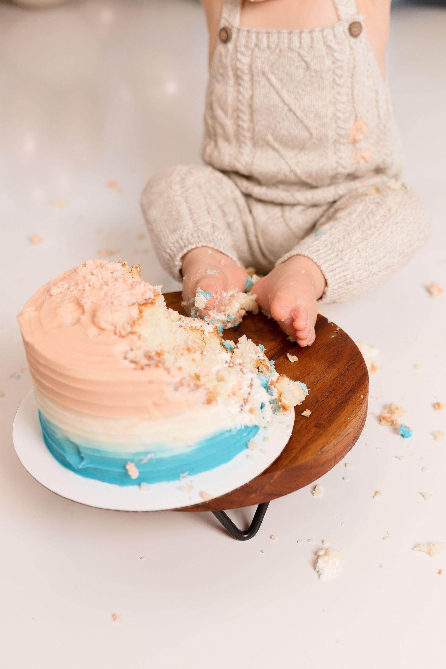 Close-up of cake smash session with peach and blue frosted cake.