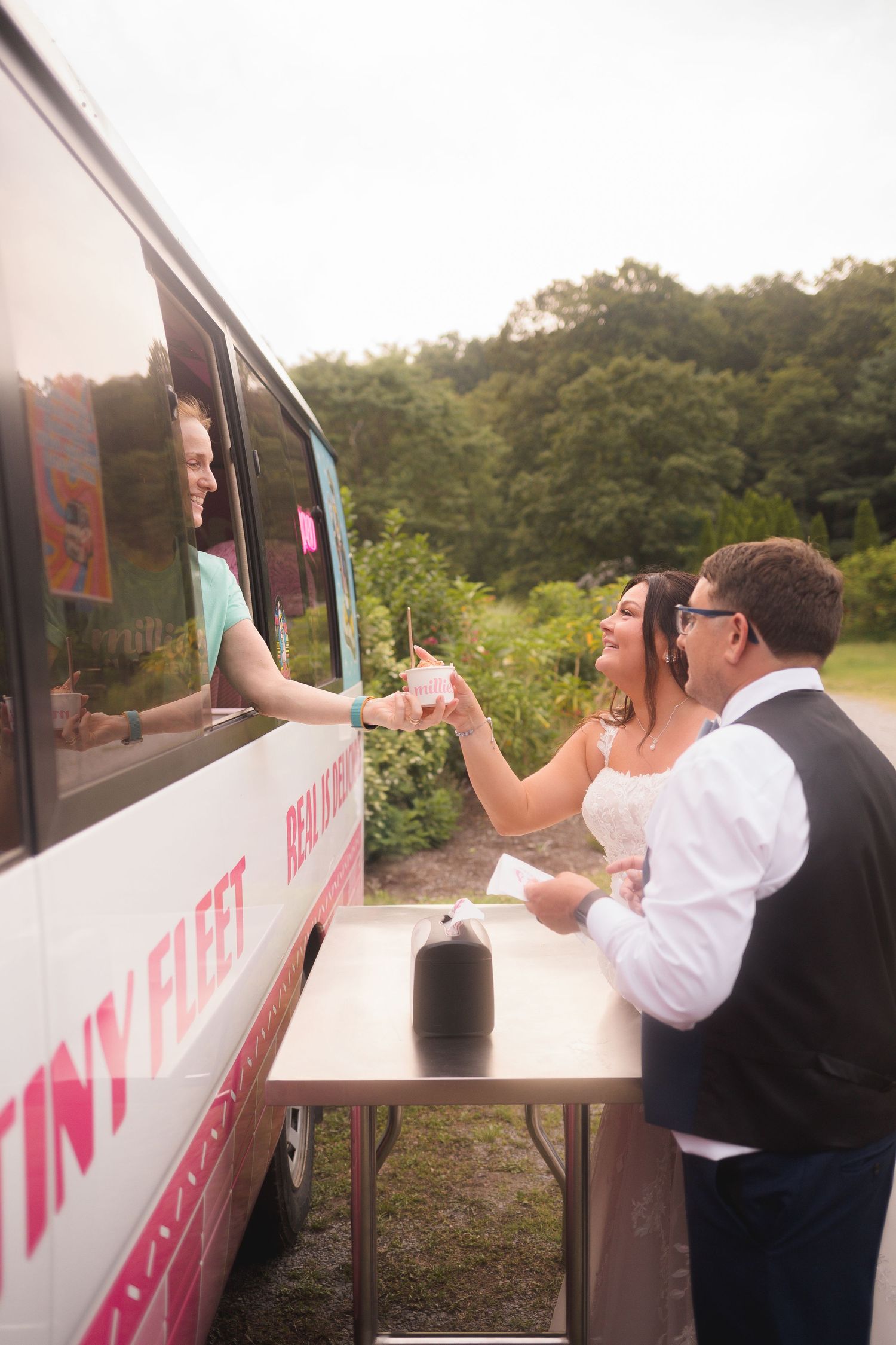 Wedding guests interact with a food truck vendor at an outdoor reception venue.