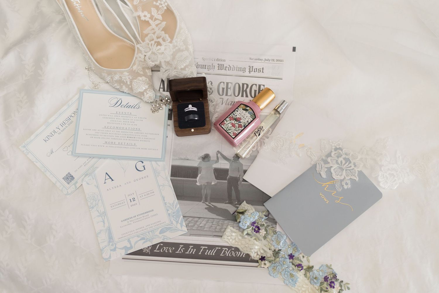 Wedding details flatlay with ring box, invitations and delicate lace accessories.