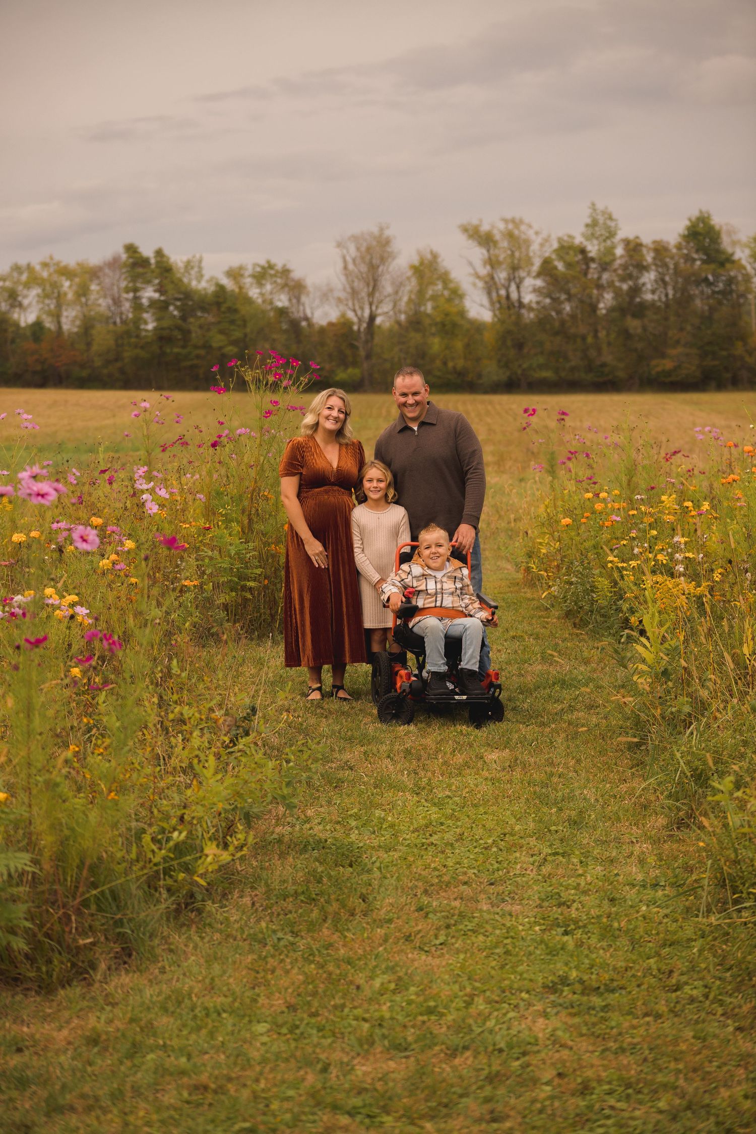 A family poses together in a wildflower meadow during golden hour.