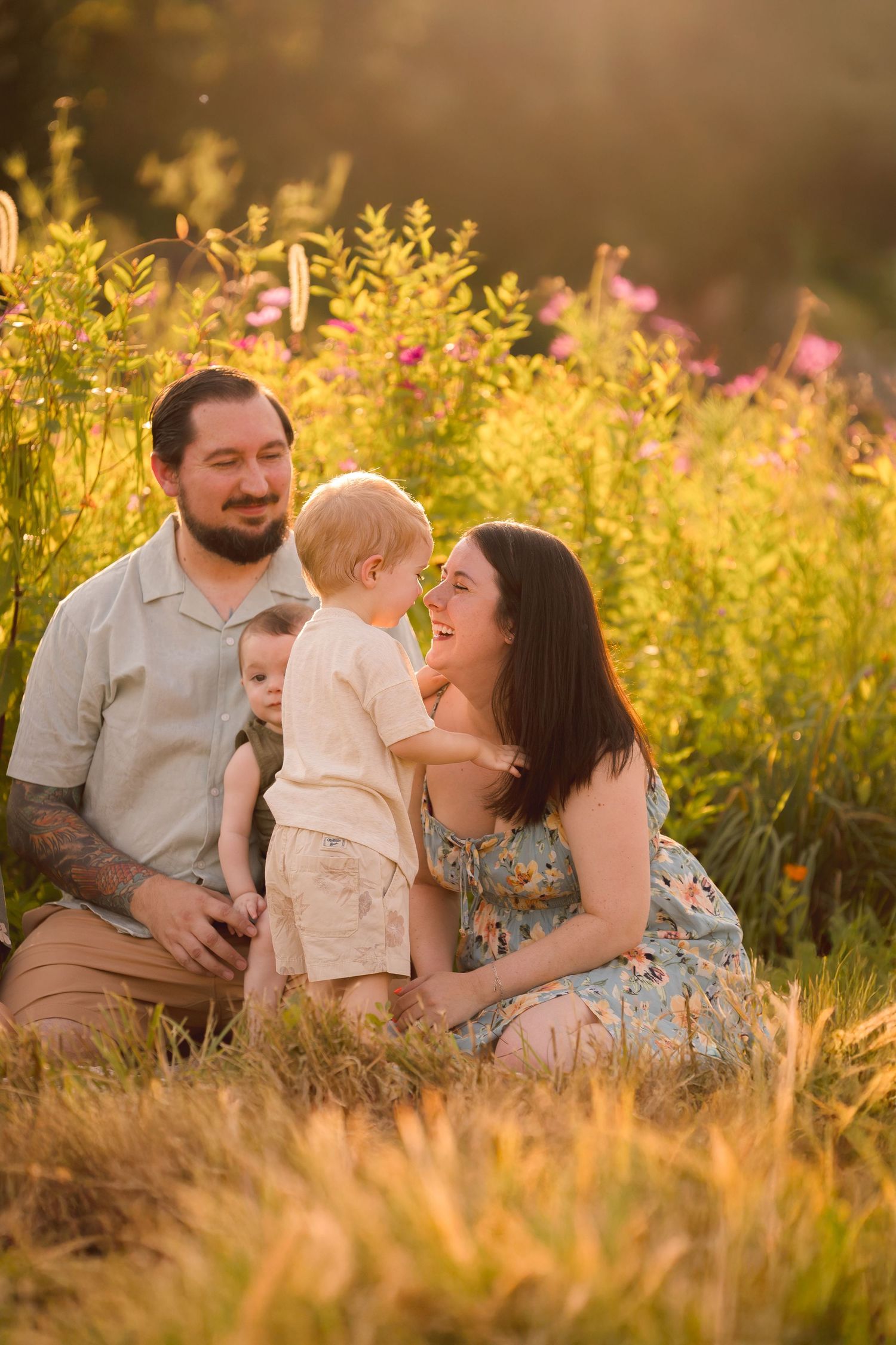 A tender family moment captured in a sun-drenched meadow with wildflowers.