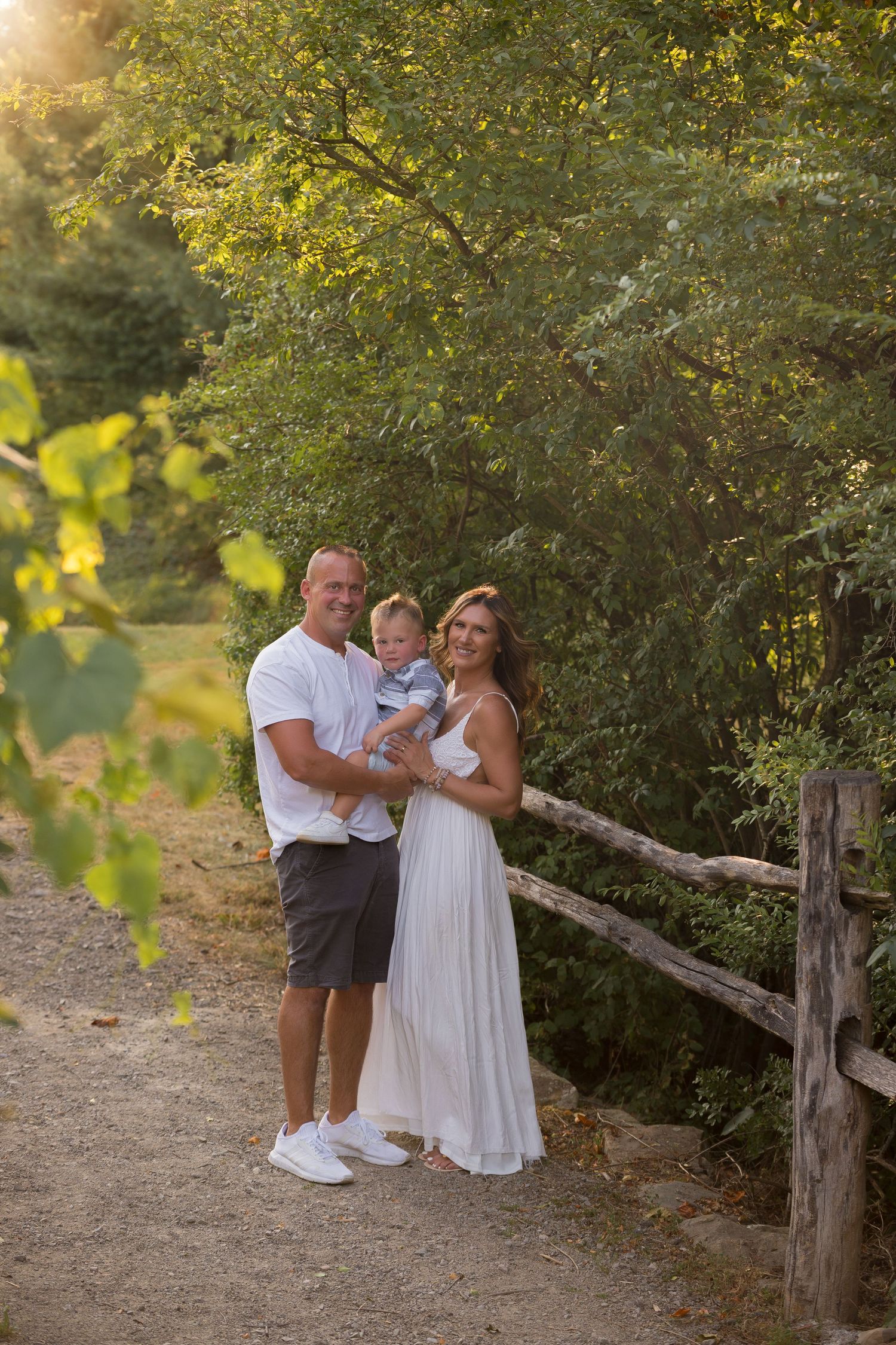 Family posing together against natural foliage backdrop in evening light.