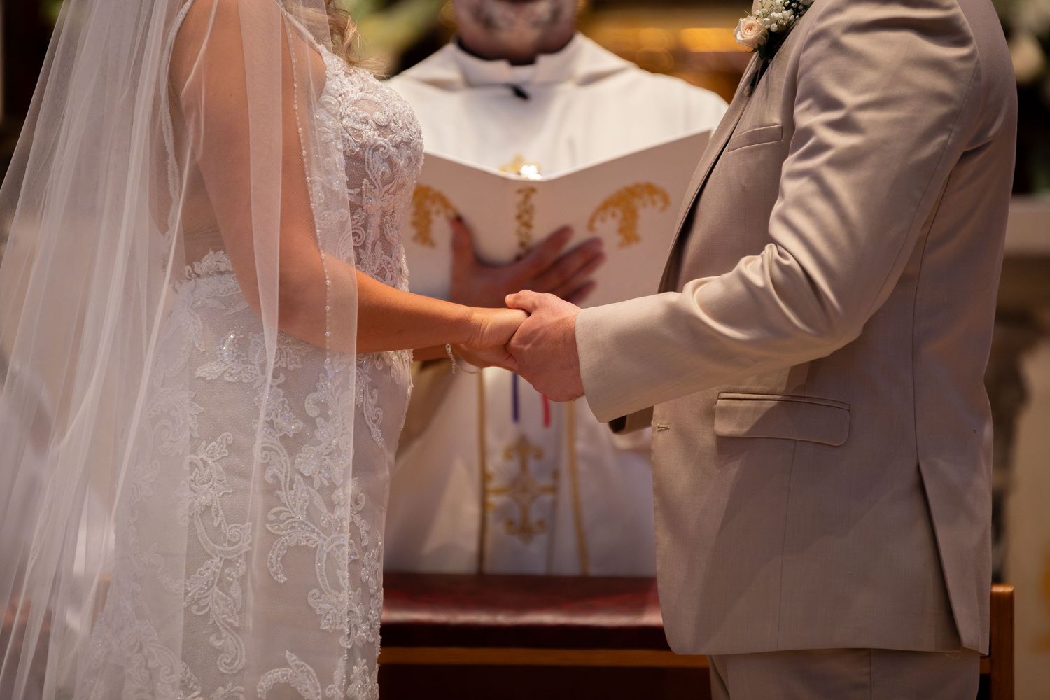 Close-up of wedding ceremony with hands joined during vow exchange.