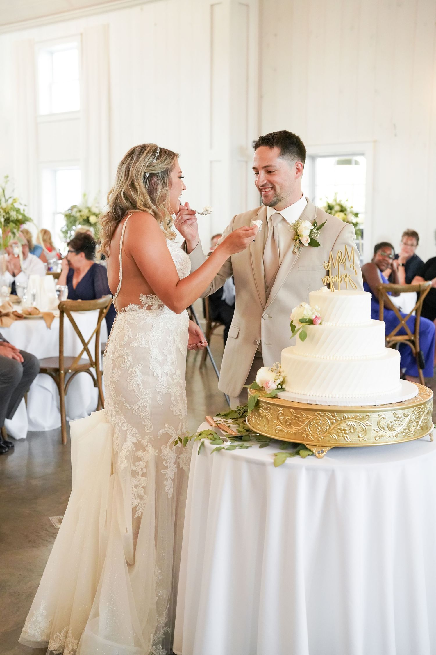 Wedding cake cutting moment at reception with elegant white tiered cake.