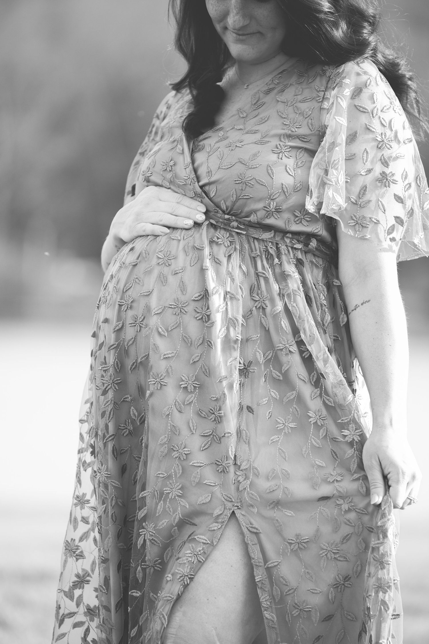 Black and white portrait highlighting the details of a lace maternity dress.