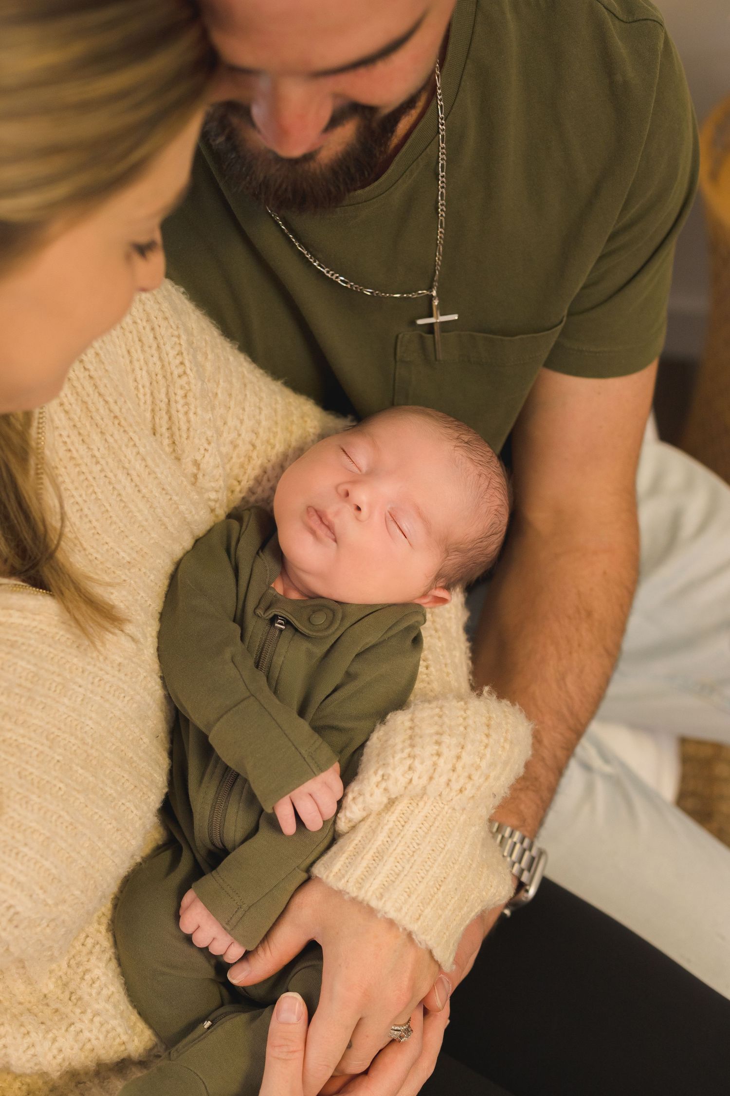 Tender family moment with infant wearing olive green outfit.