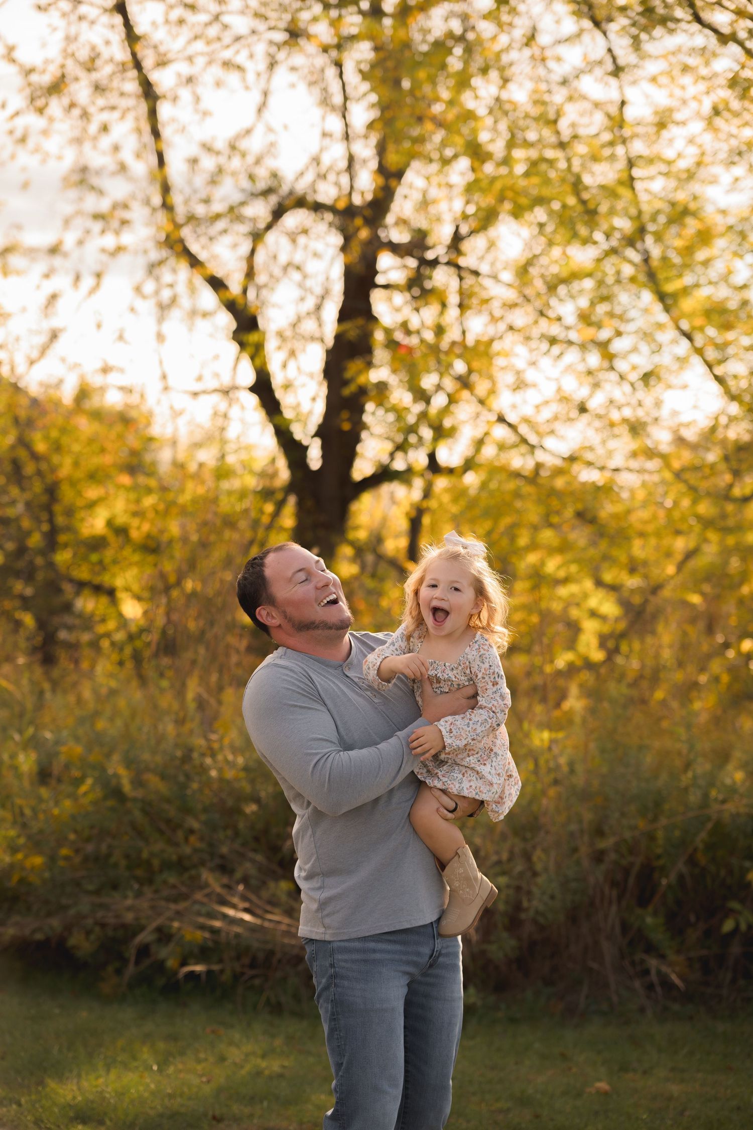 Joyful moment between parent and child laughing together in autumn setting.