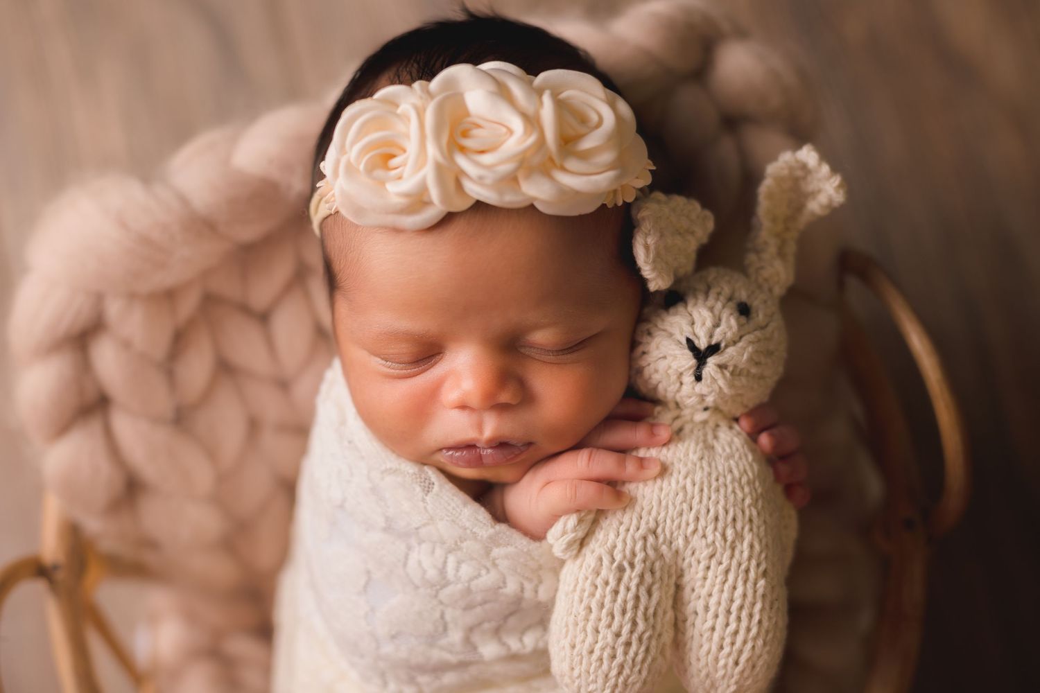 Sweet newborn photo with white wrap and decorative knit teddy bear accessory.