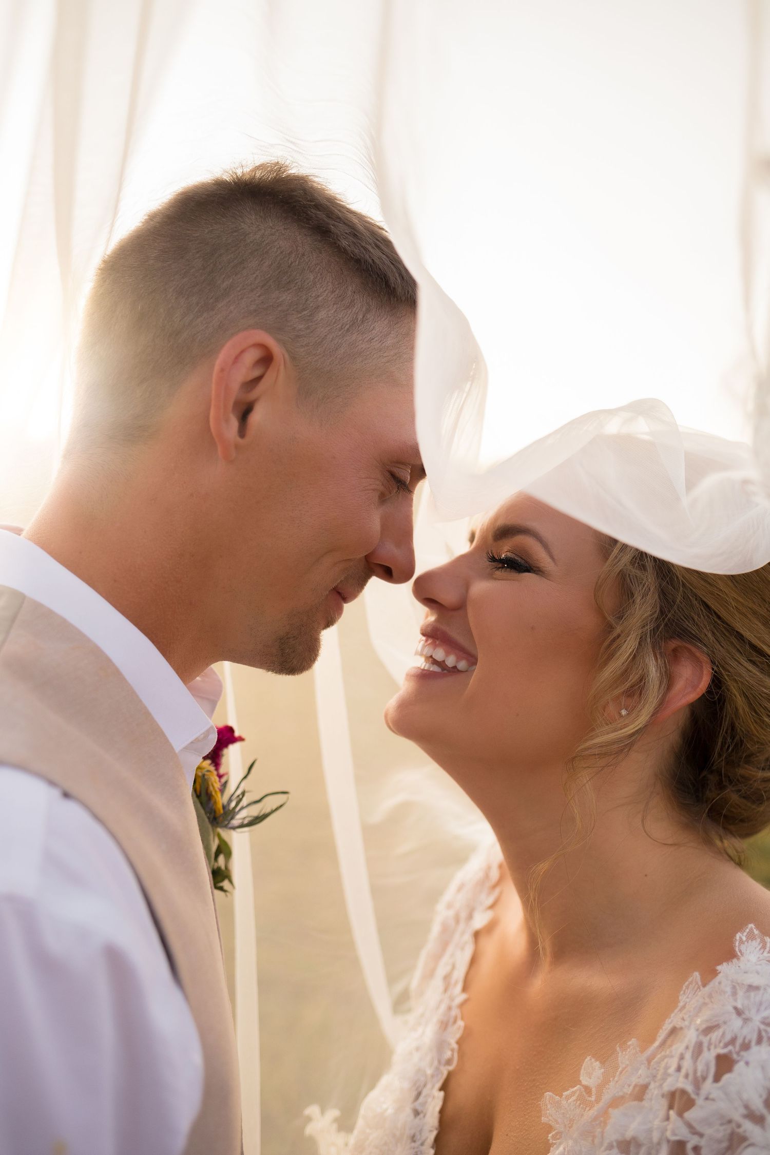 Romantic wedding portrait of couple sharing an intimate moment in soft window light.