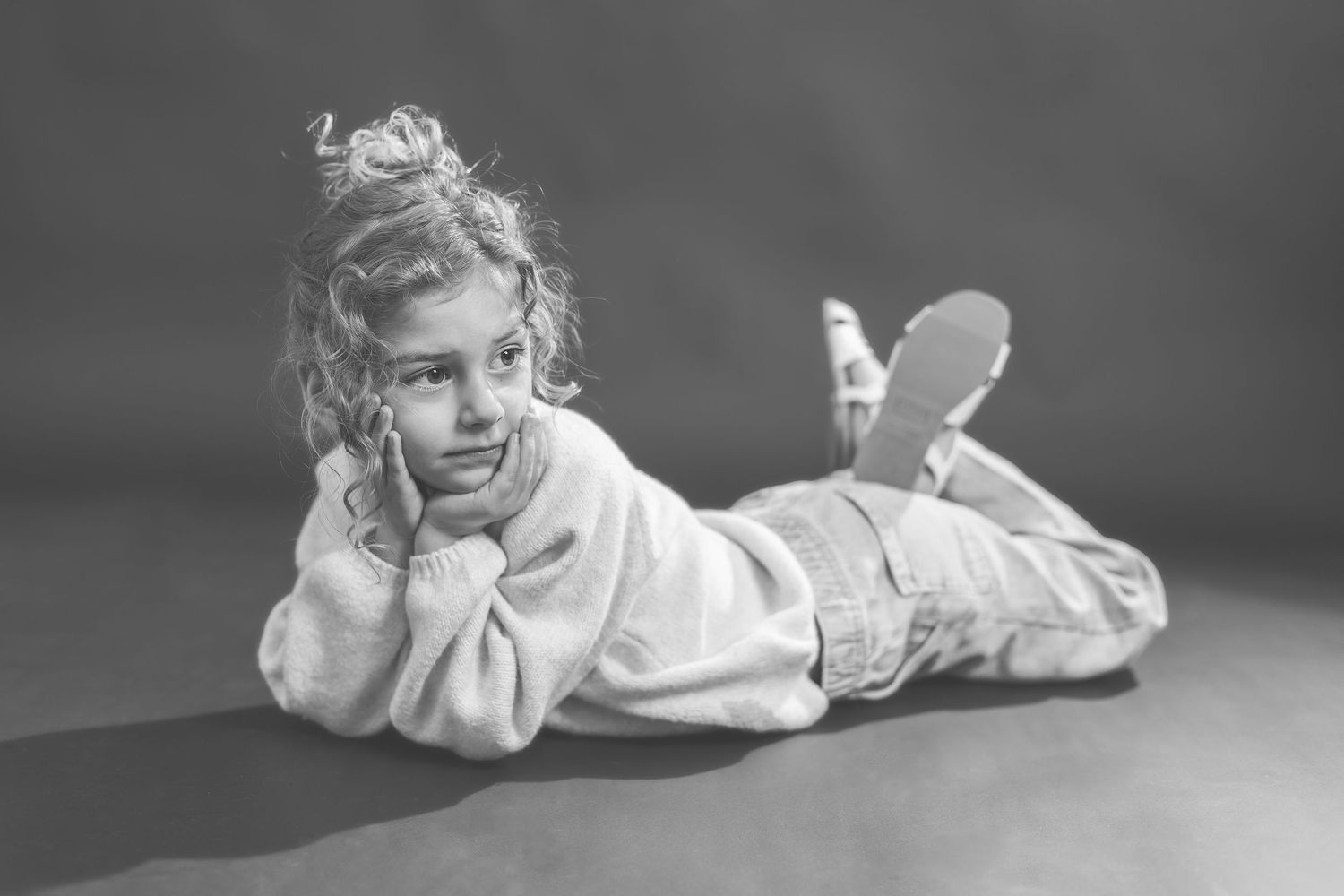 A black and white artistic photo series showing a person lying down in various relaxed poses on a light surface.