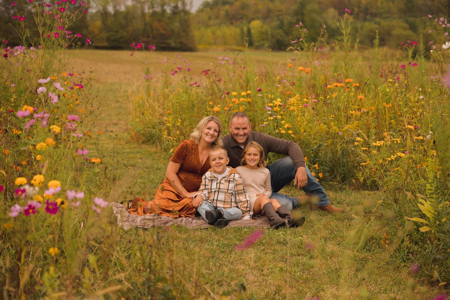 Family sitting together in wildflower meadow during sunset photo session.