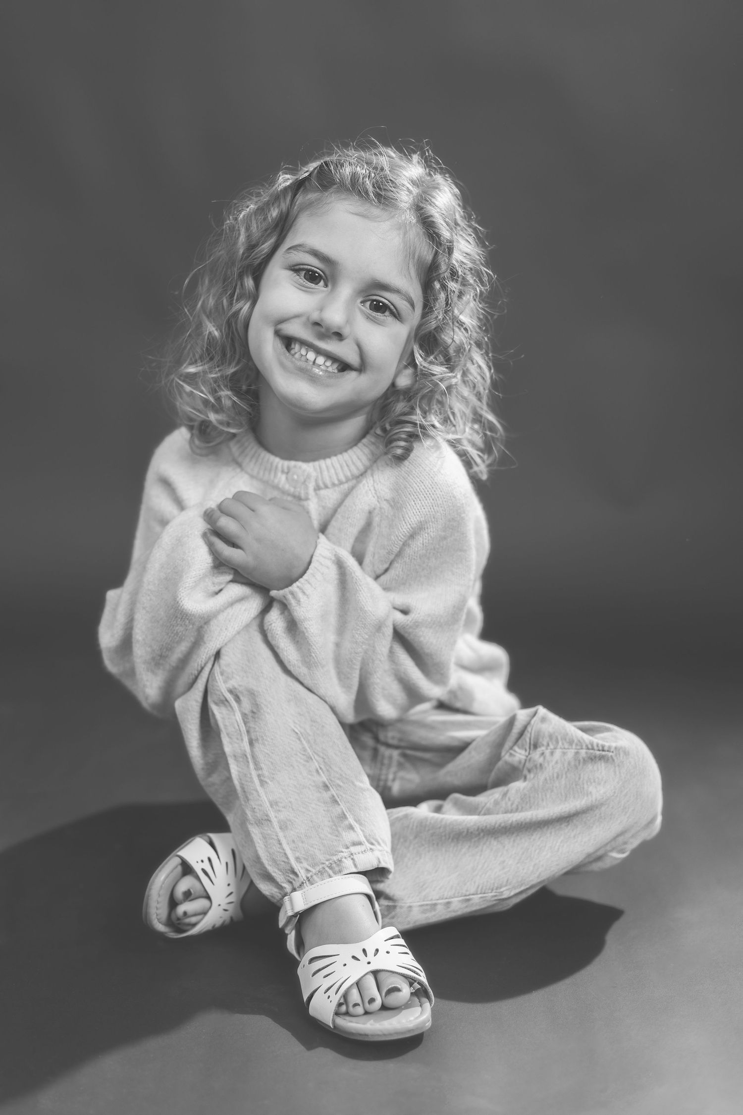 A black and white photo sequence showing a young child in a sweater making playful expressions and poses.