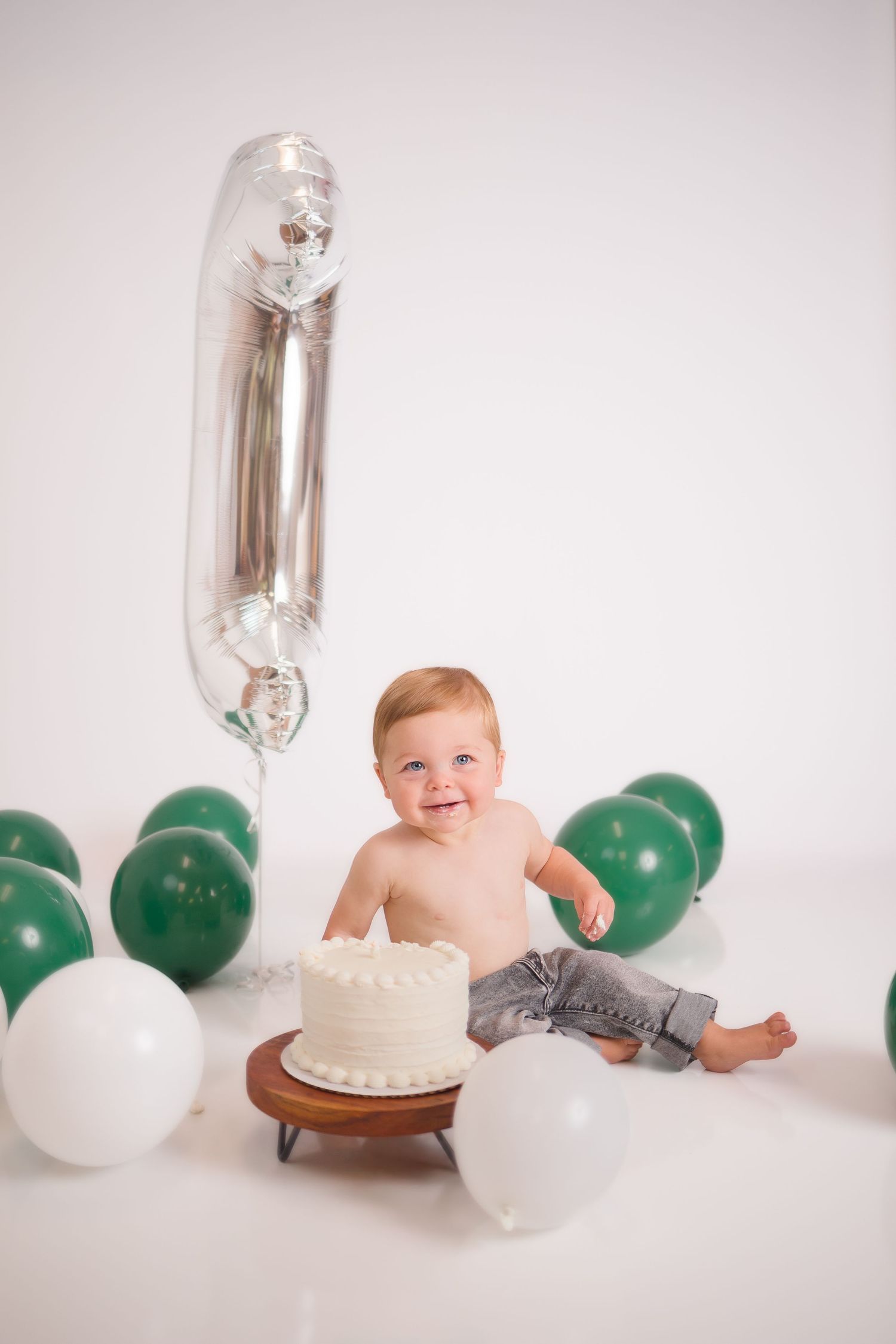 A festive first birthday setup with balloons, cake, and silver number one balloon.