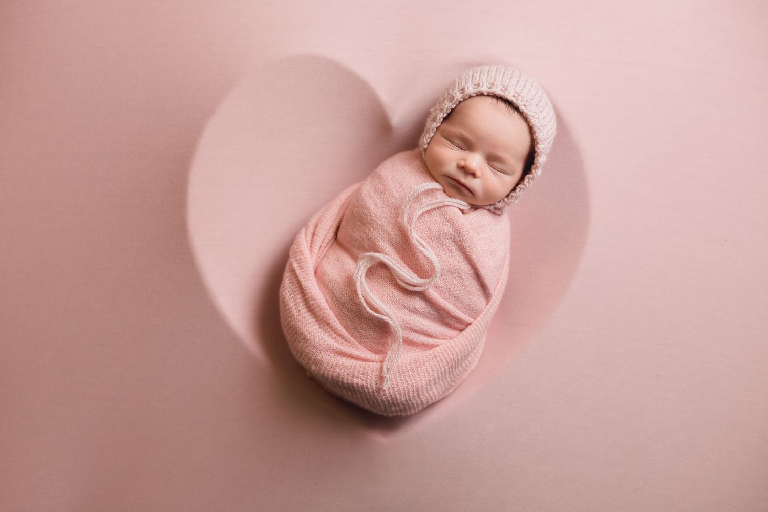 Pink fabric backdrop arranged in soft folds for newborn photography session.