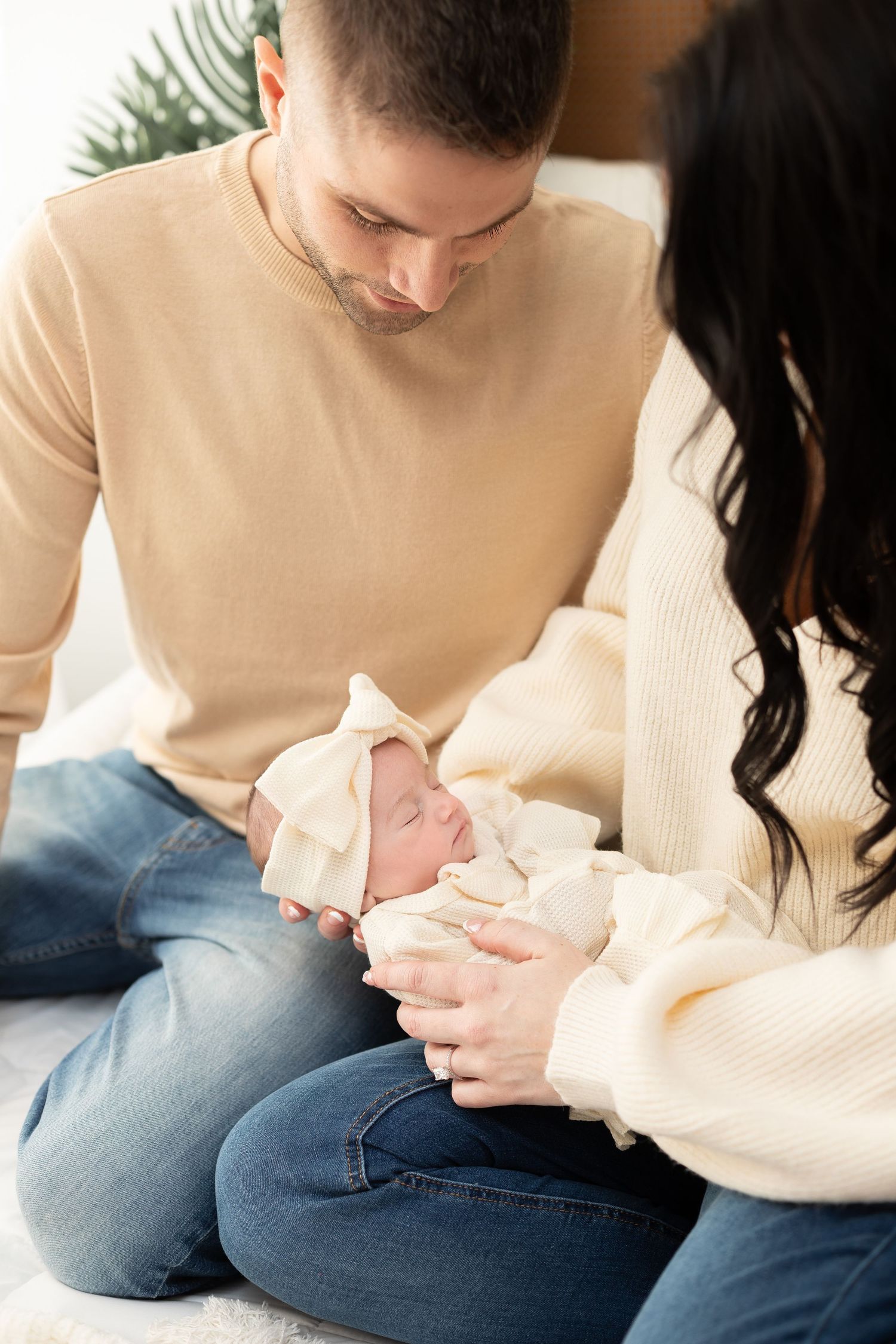 Intimate indoor newborn photography session with cream sweater and soft lighting.