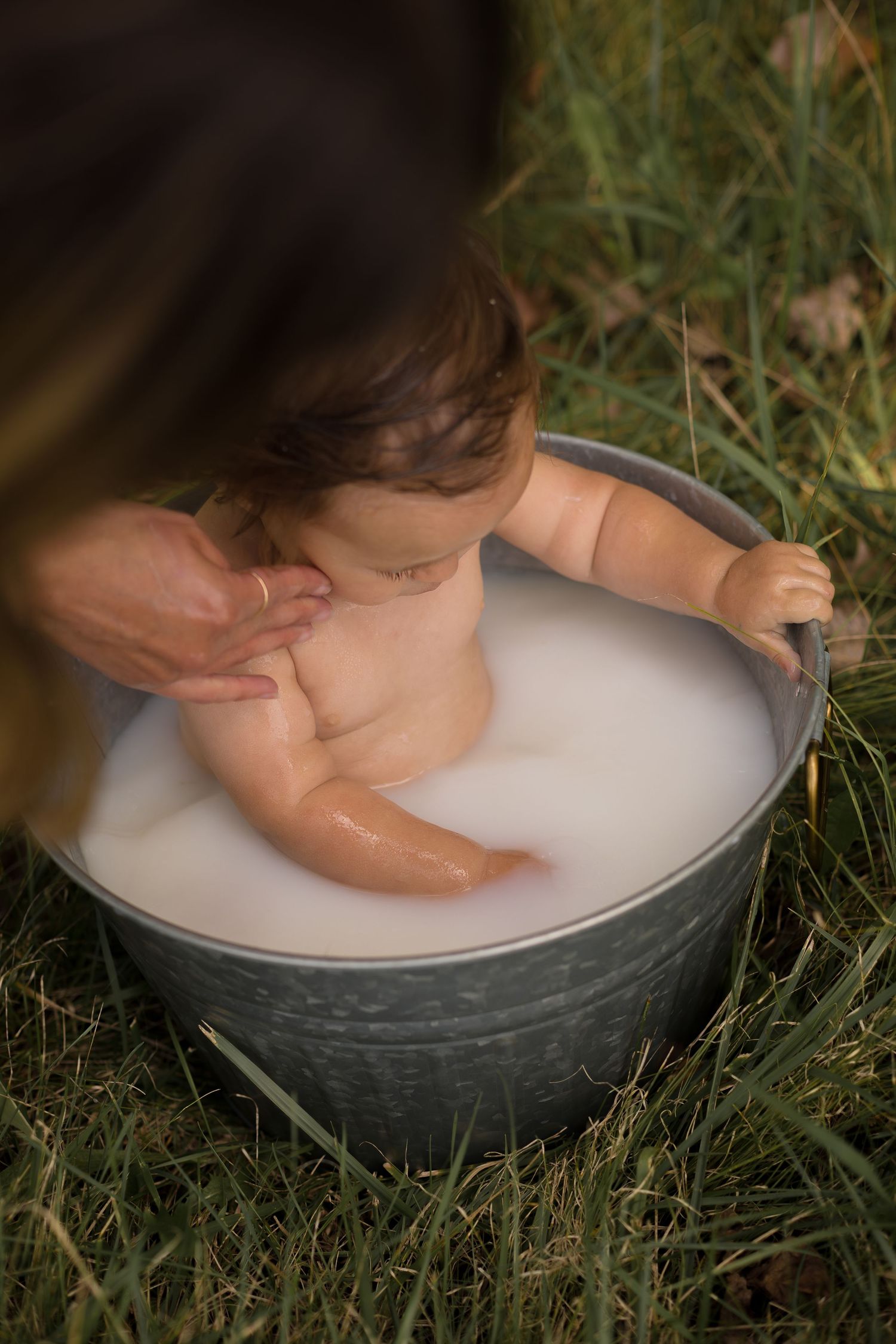 Intimate milk bath photography session with soft lighting and natural outdoor backdrop.