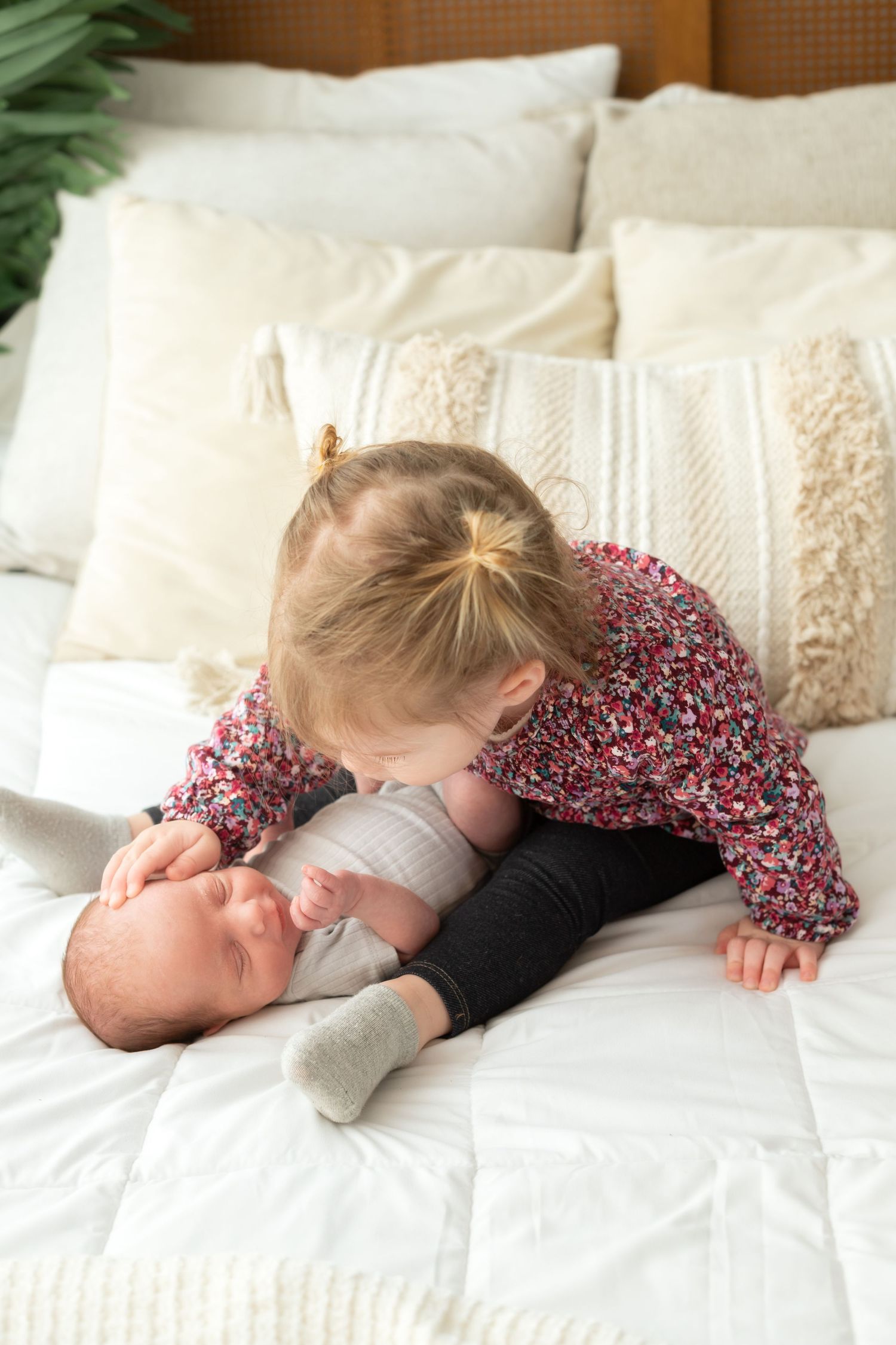 Siblings sharing a quiet moment together on white bedding.