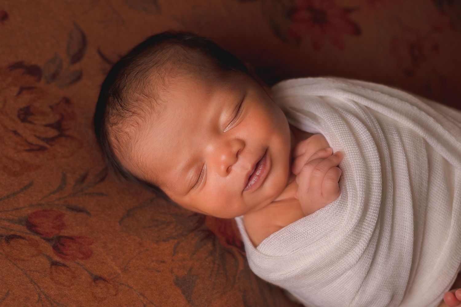 Artistic black and white newborn portrait with soft white wrapping.