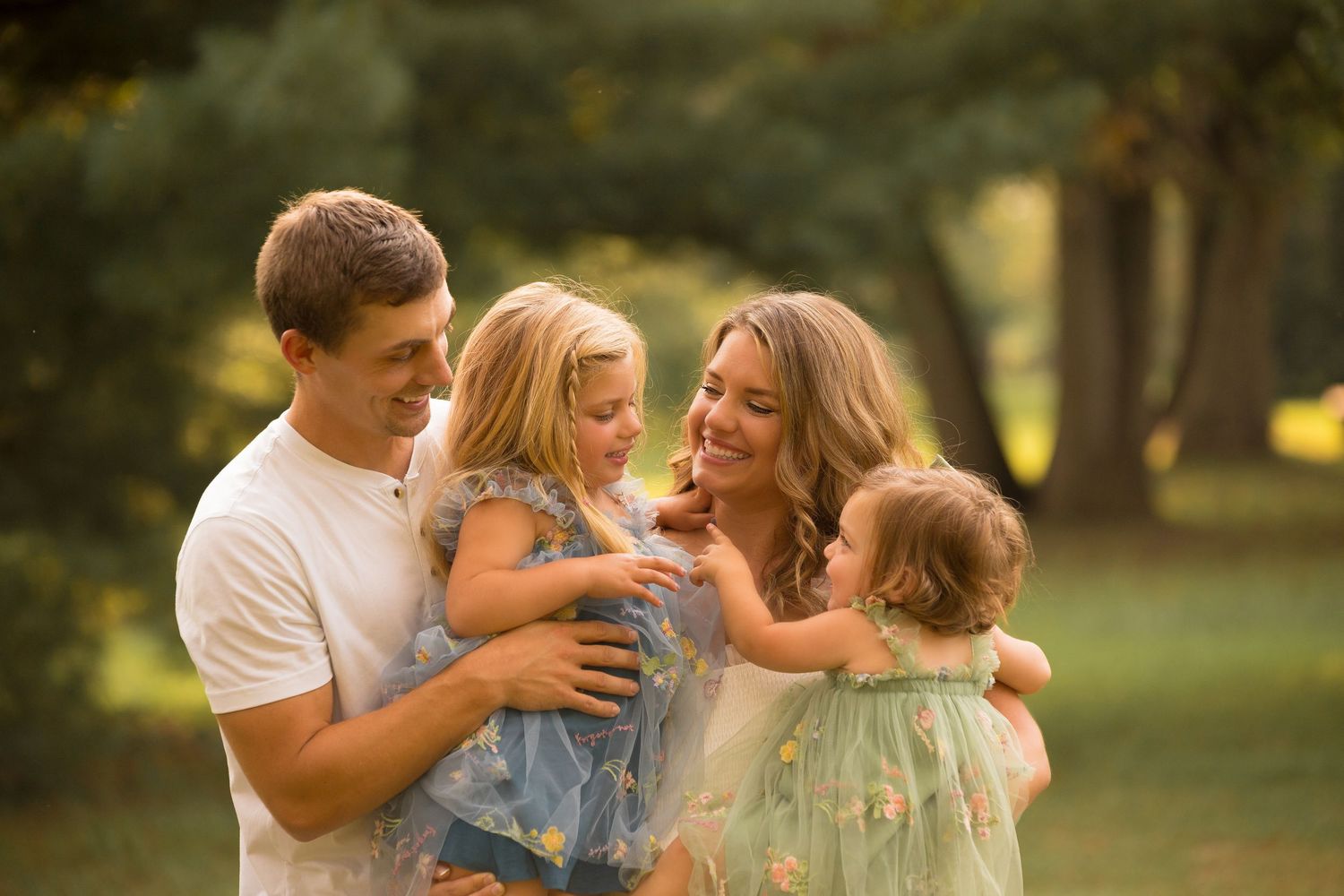Family sharing a joyful moment together in a sunlit park setting.
