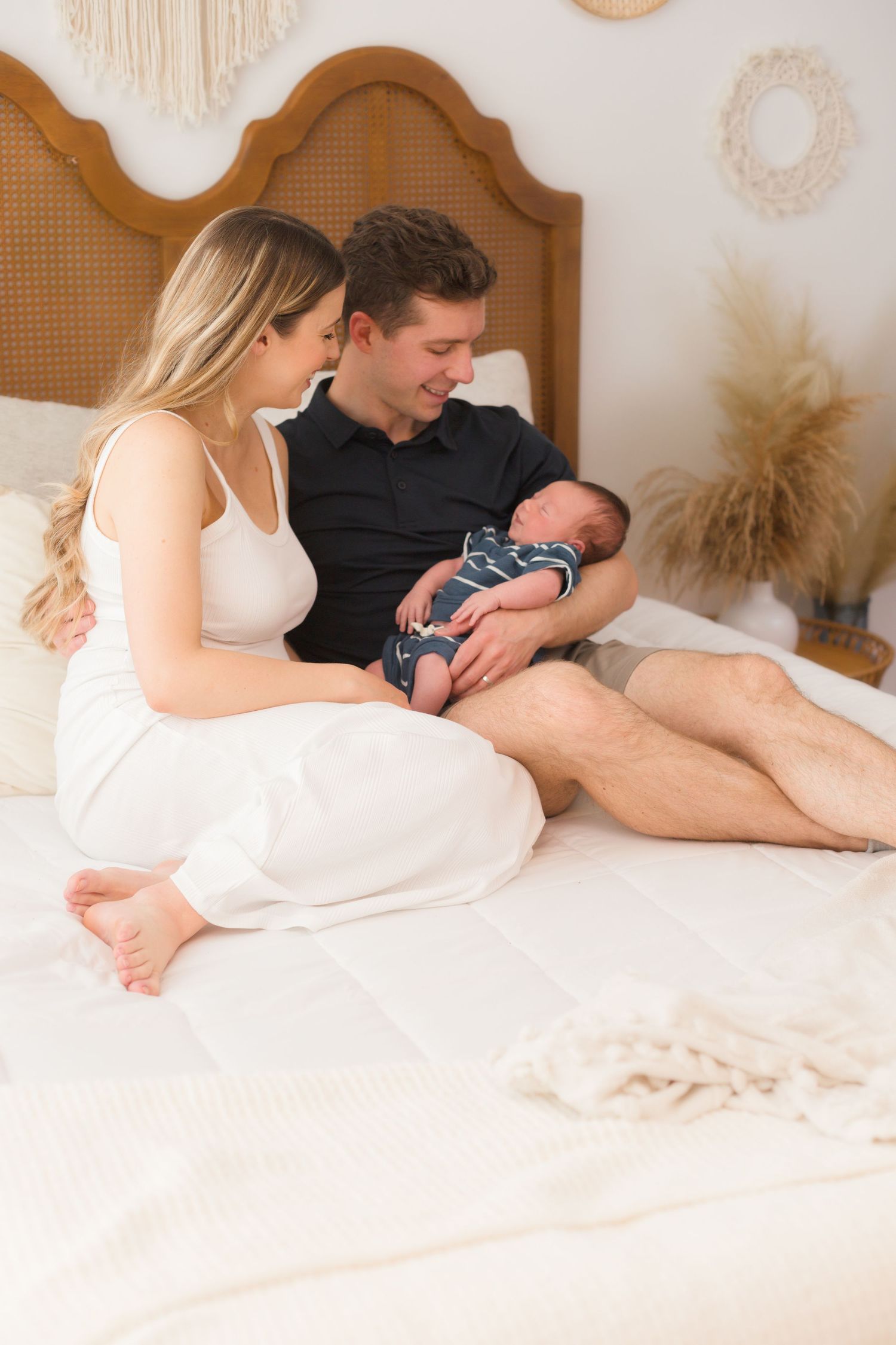 A tender family moment captured on a white bed with neutral decor.