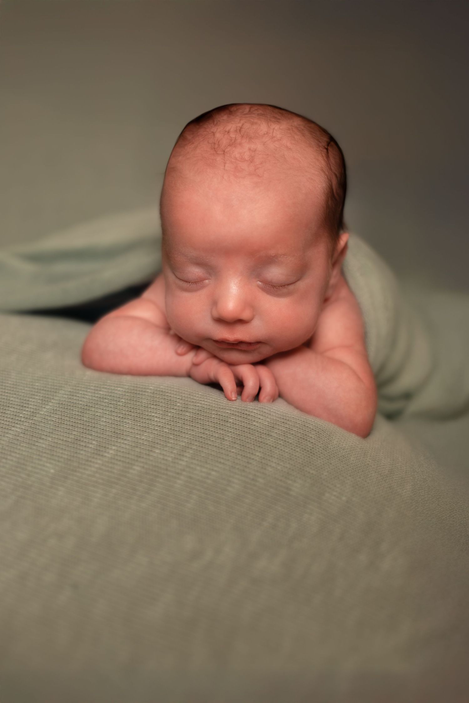 Series of artistic close-up shots showing peaceful sleeping newborn on gray textile.