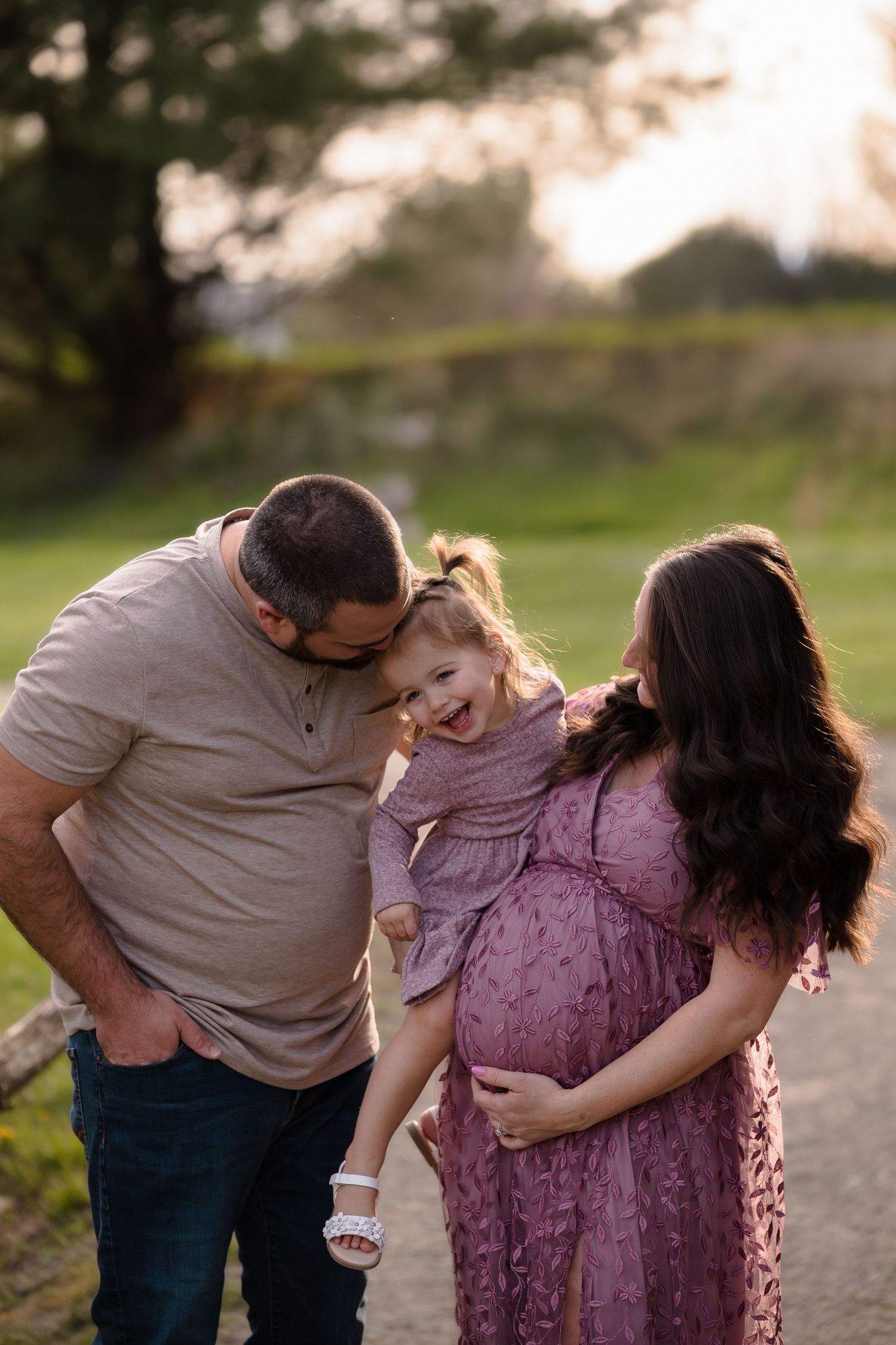 An intimate family portrait showing joyful interaction on a nature path at sunset.