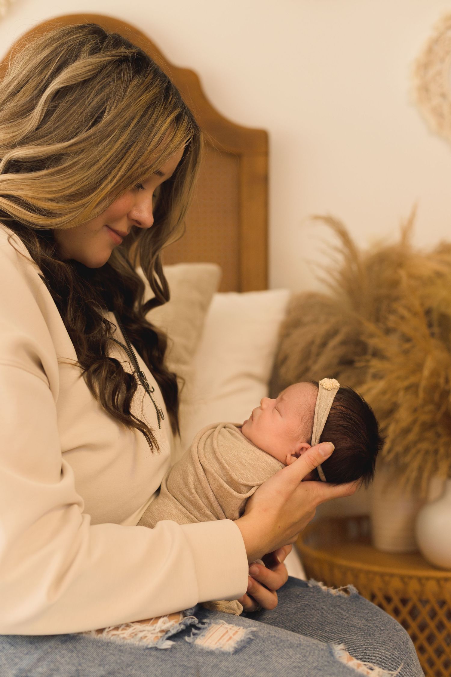 Mother in beige sweater holding newborn baby during lifestyle photo session.