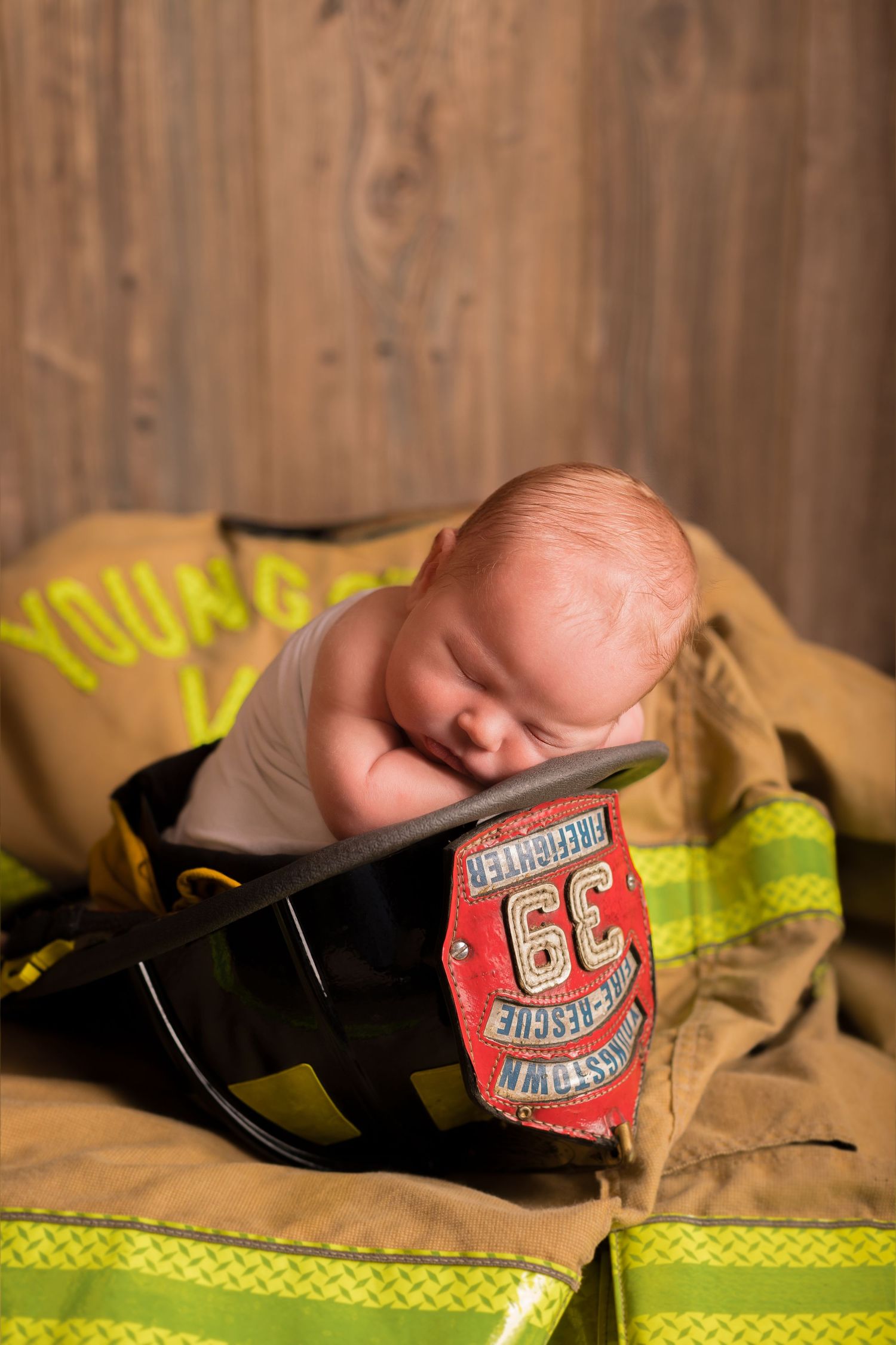 A newborn photo session featuring firefighter gear and safety equipment.