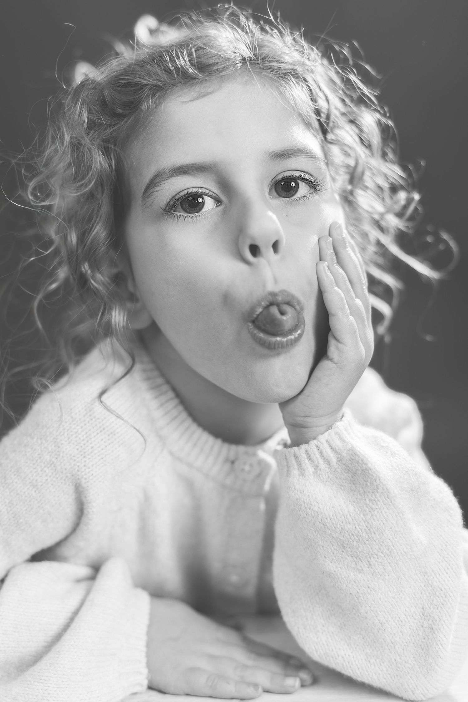 A series of black and white portraits showing playful expressions and poses in a white sweater.
