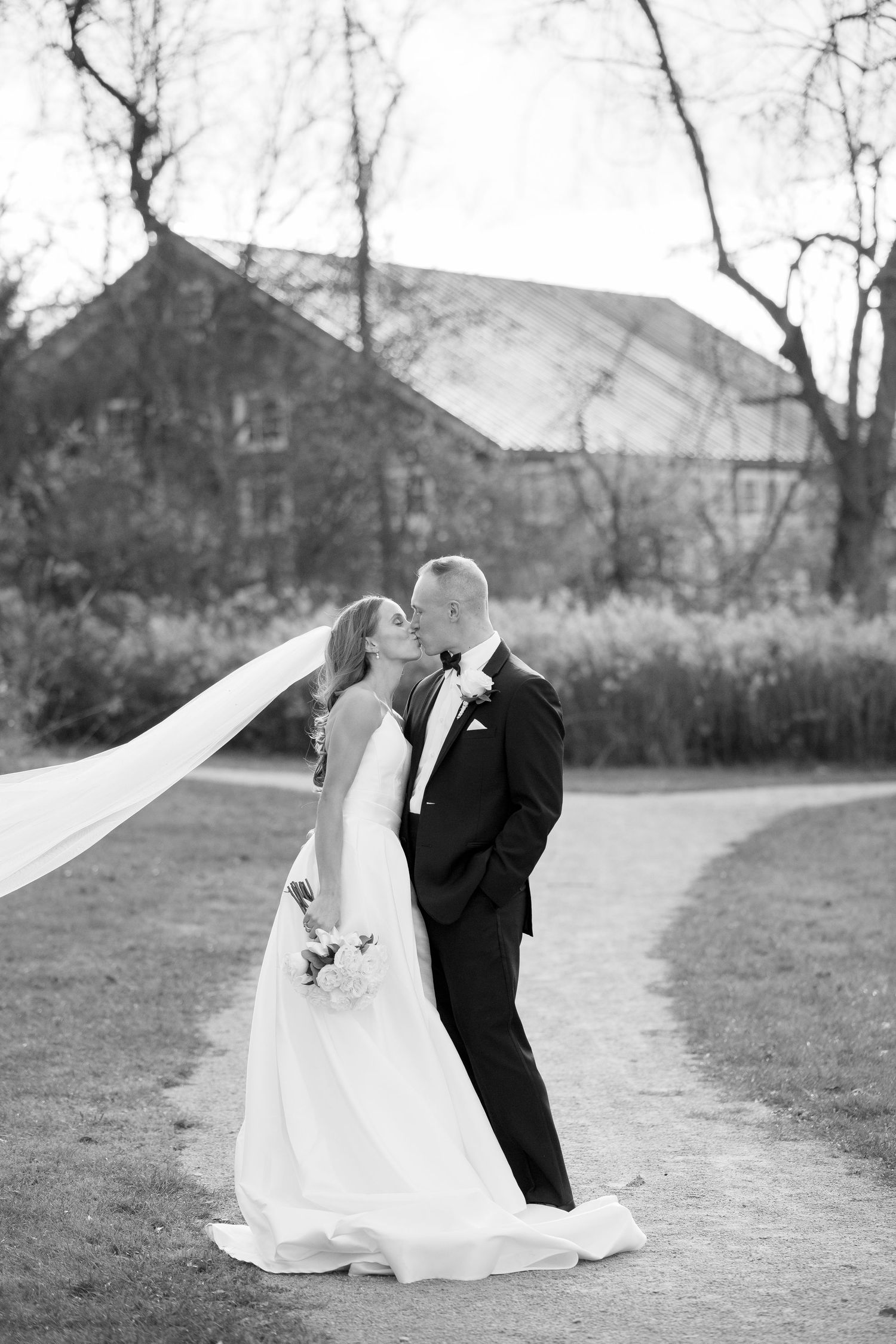 Black and white photo of wedding couple dancing on outdoor path.