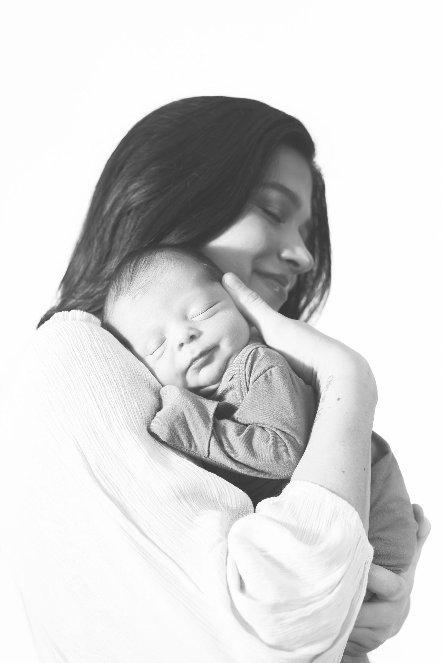 A gentle black and white portrait capturing an intimate maternal moment.
