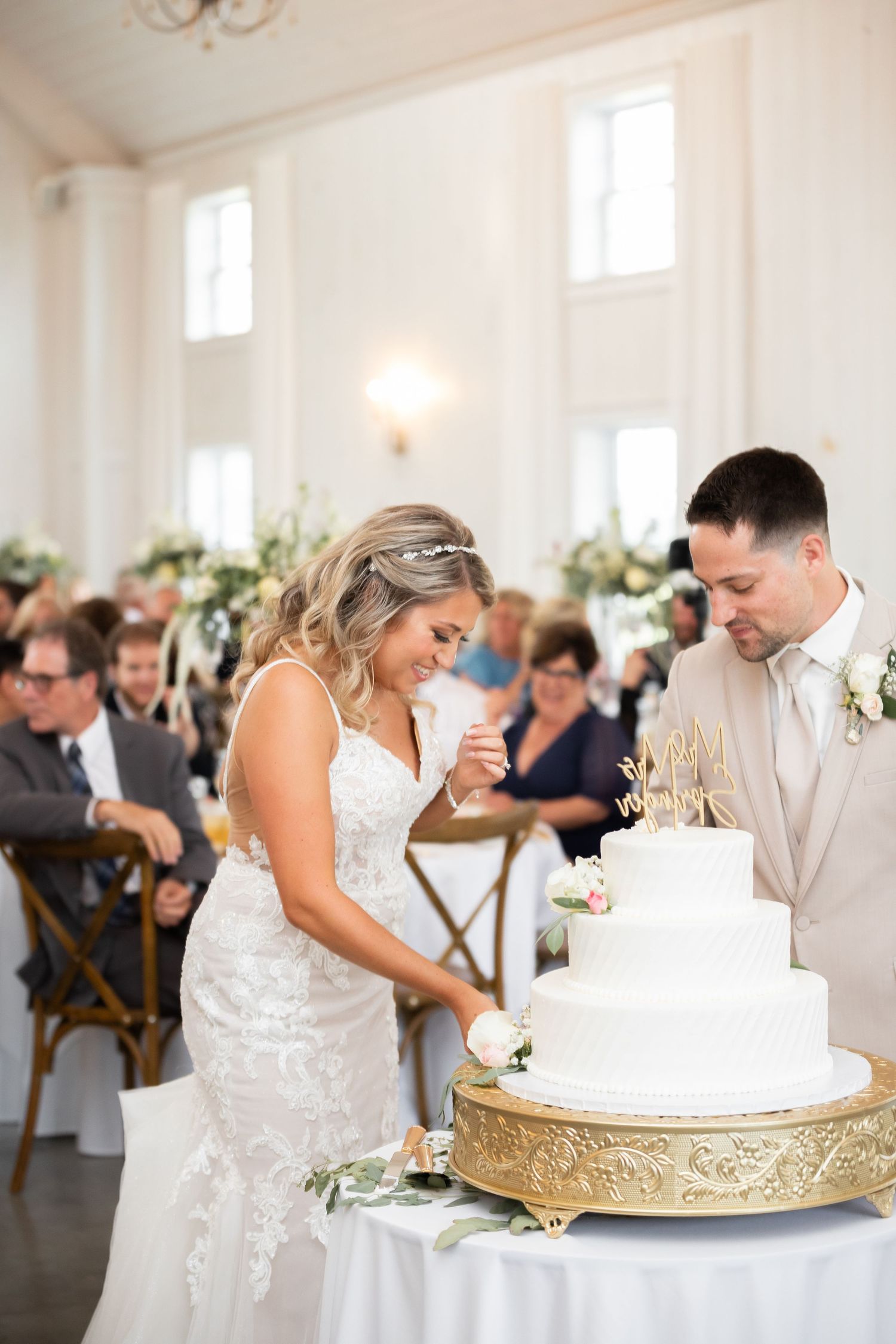 Bride and groom cut their elegant white wedding cake together at their reception.