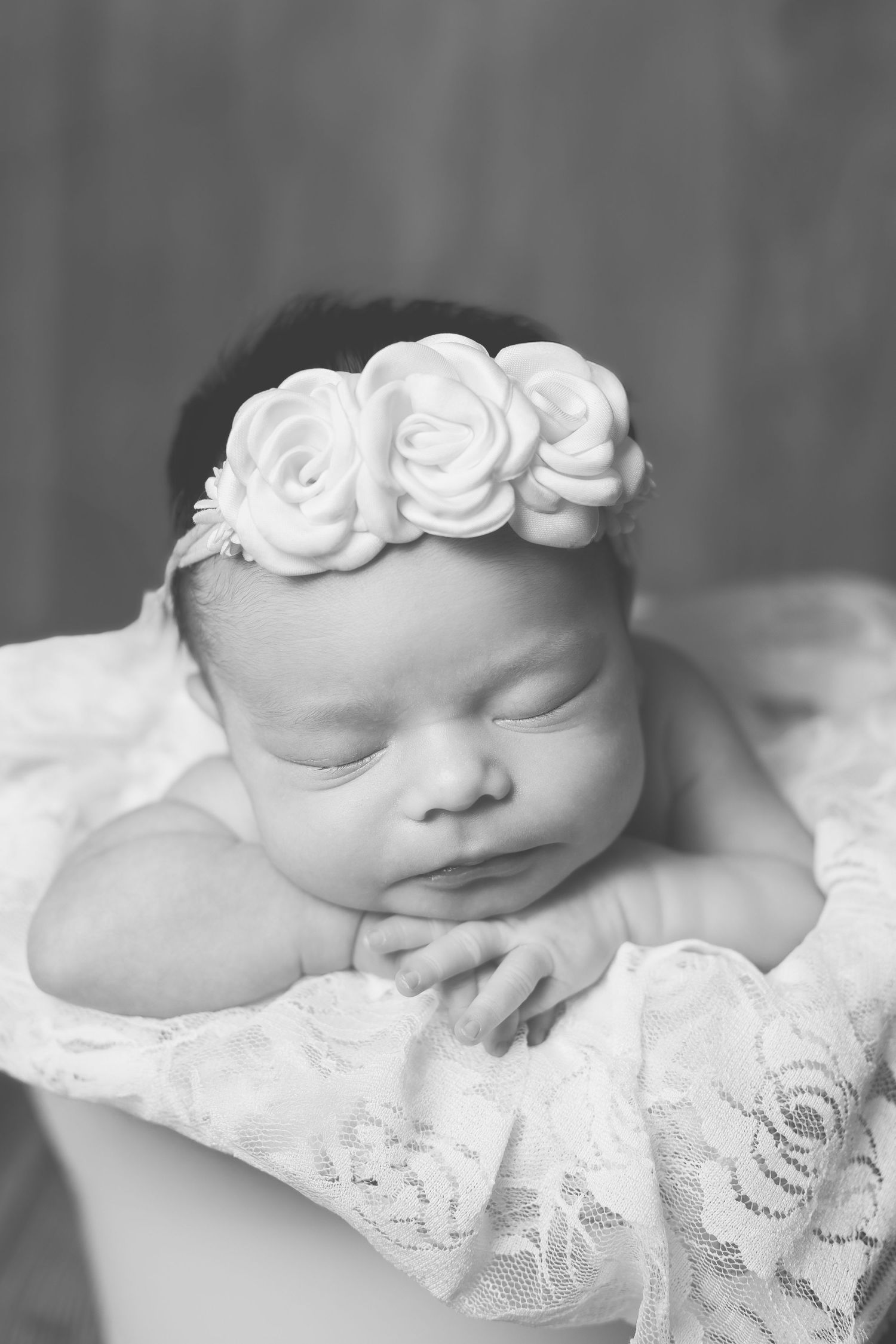 Black and white portrait of infant wearing delicate lace wrap and floral crown.