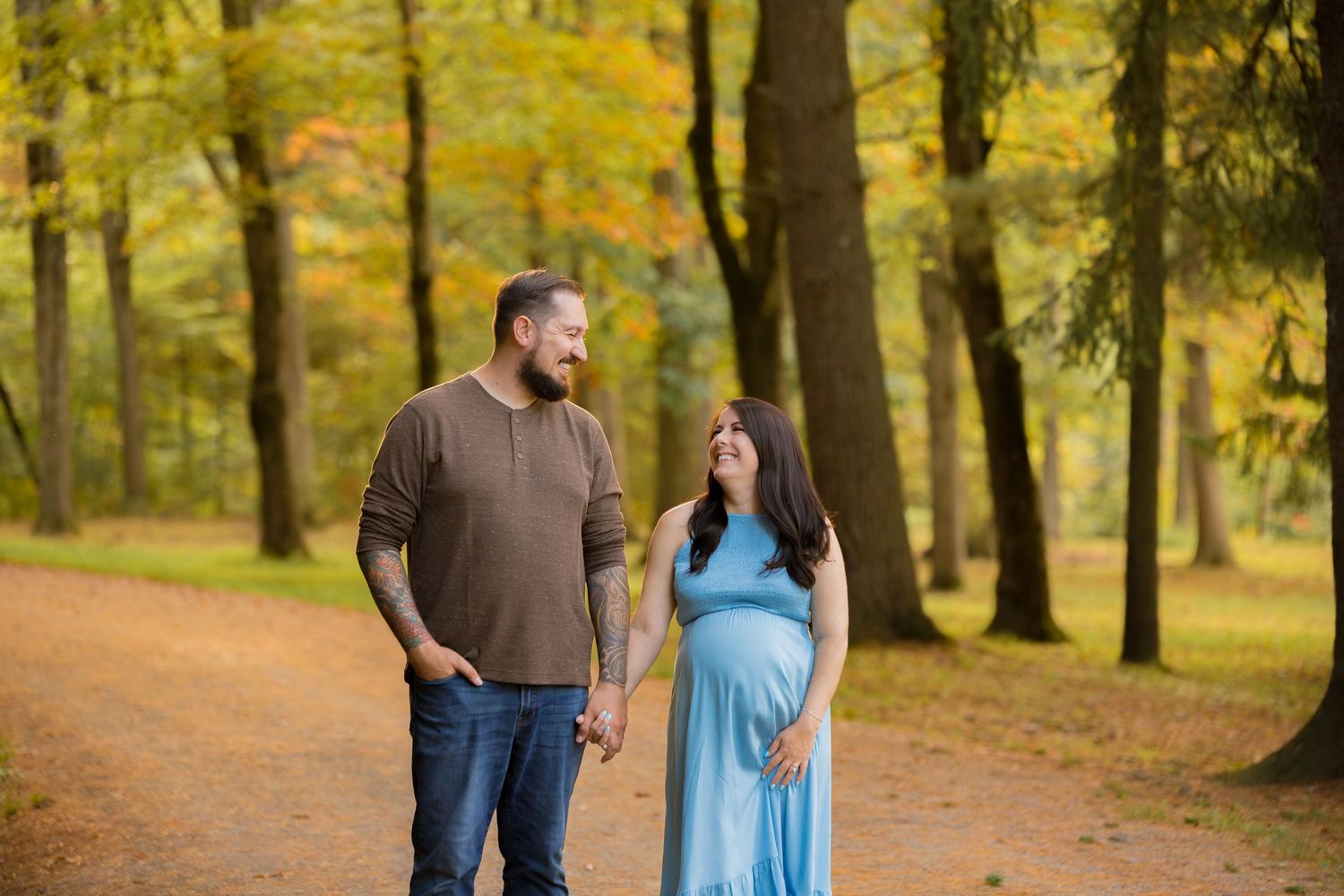 Couple walking together on autumn path surrounded by golden trees.