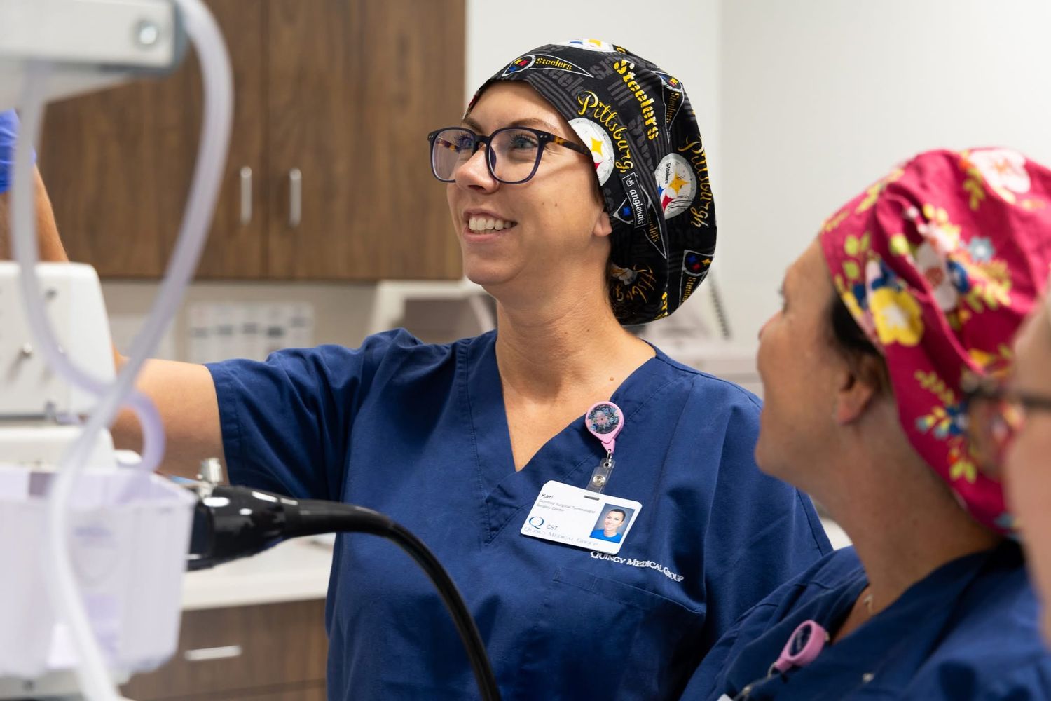 Medical staff in navy scrubs and patterned caps working together in clinical setting.