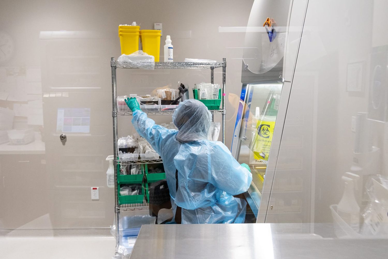 Laboratory technicians in blue protective equipment handling specimens in a clean room facility.