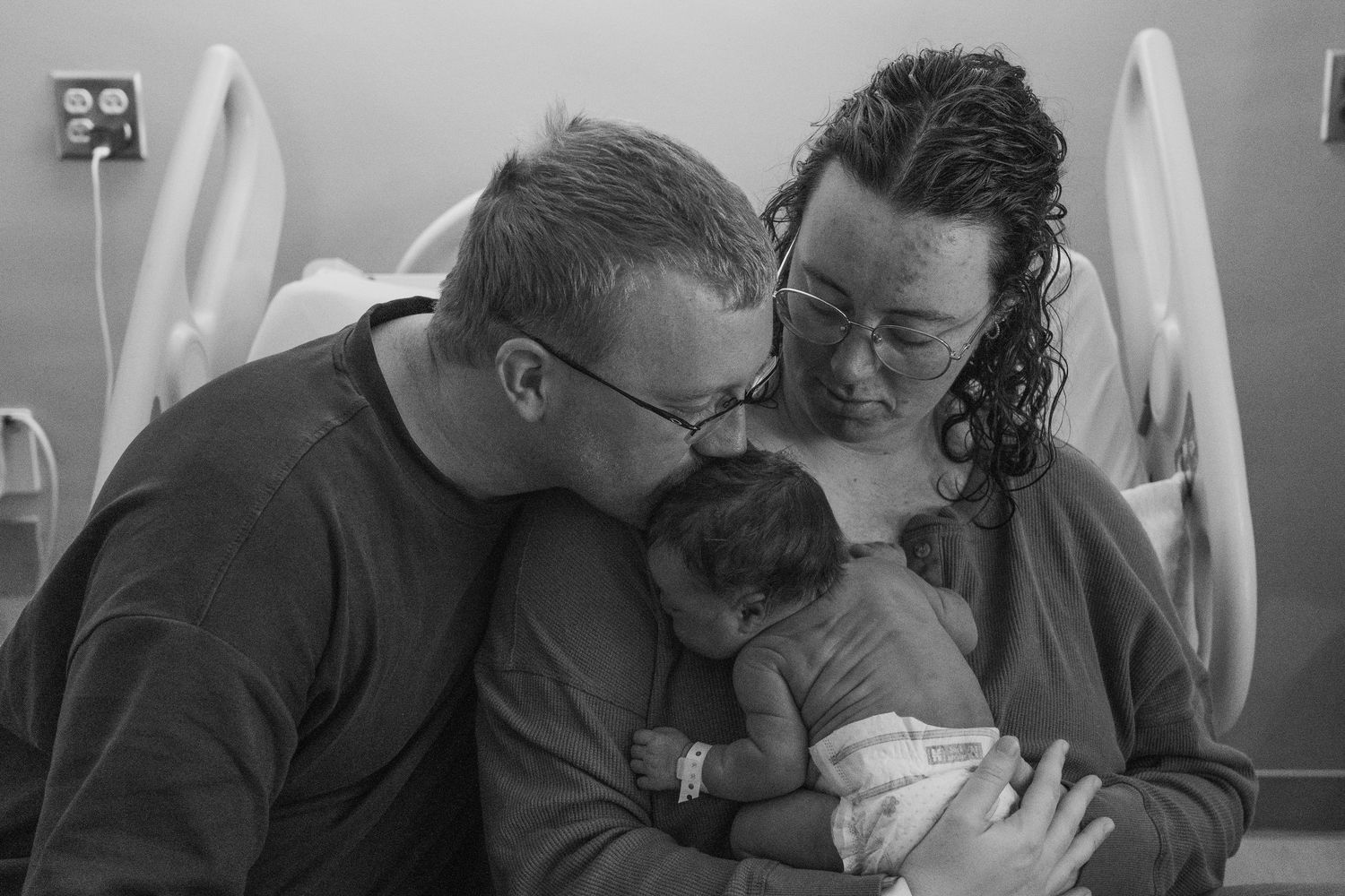 Emotional black and white hospital scene with parents attending to a newborn.