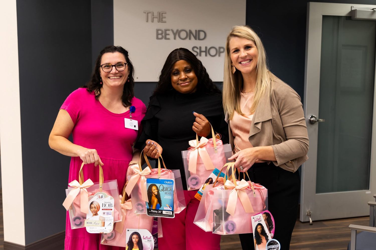 Group holding pink gift bags at indoor gathering event.