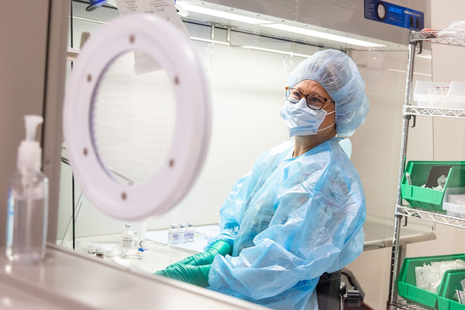 Medical staff in protective gear working in a clinical laboratory setting.