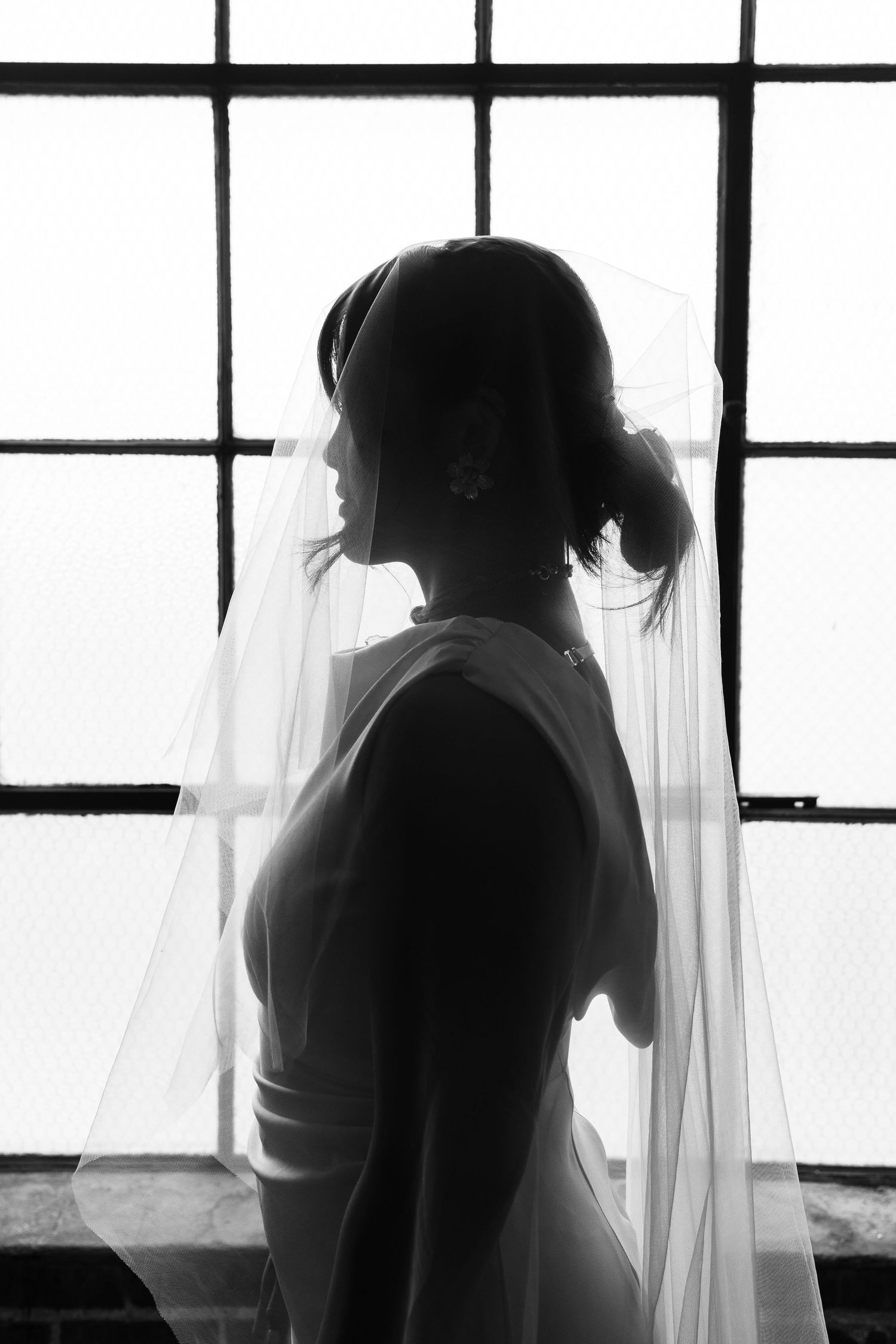 Silhouetted figures stand behind sheer white curtains in a triptych-style black and white composition.