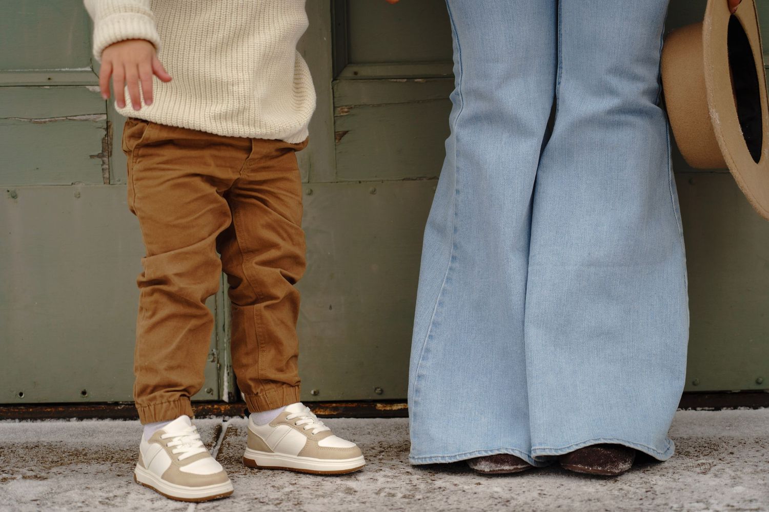 Close-up view of feet and legs standing on concrete sidewalk.