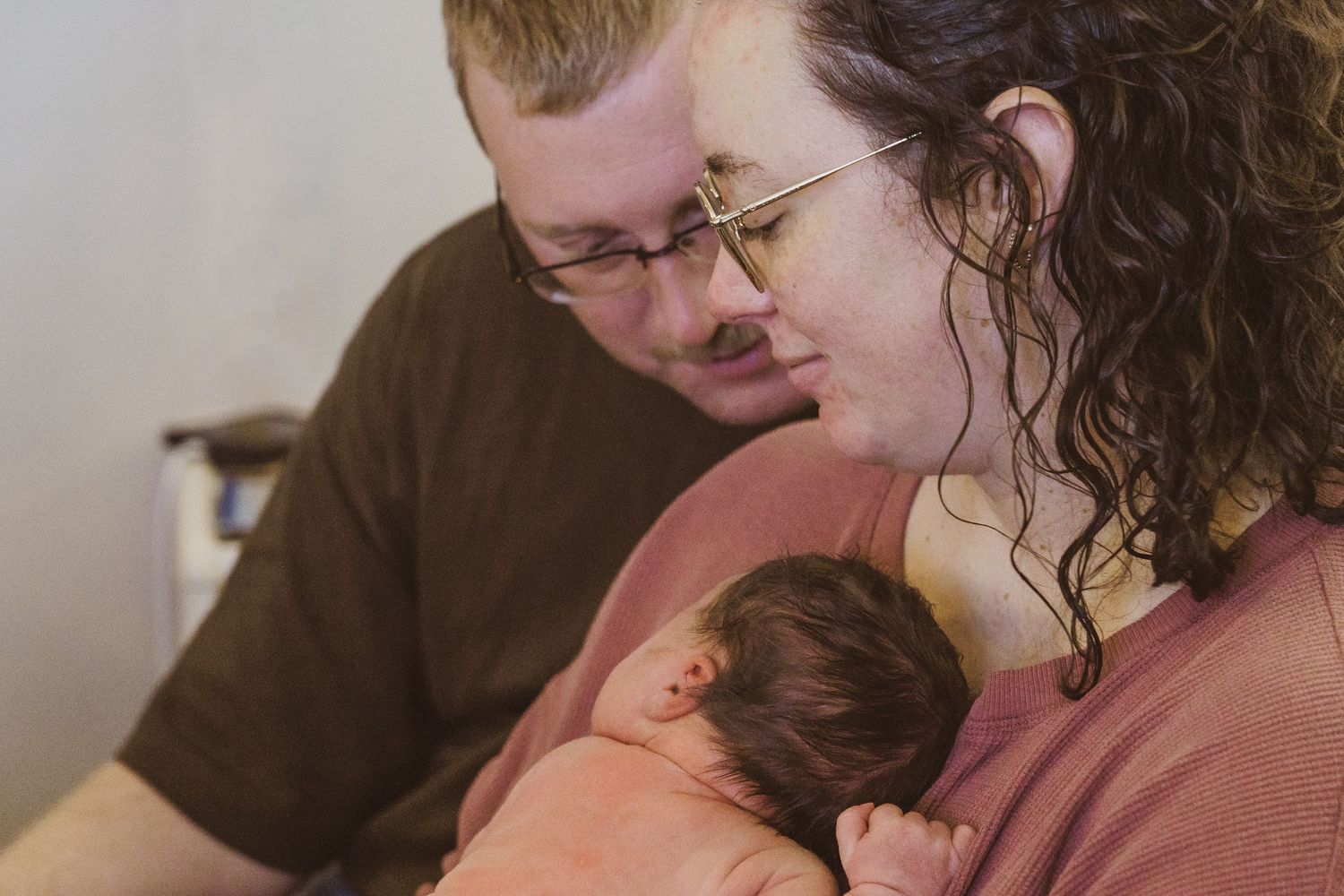 Intimate hospital photo of parents with their newborn baby.