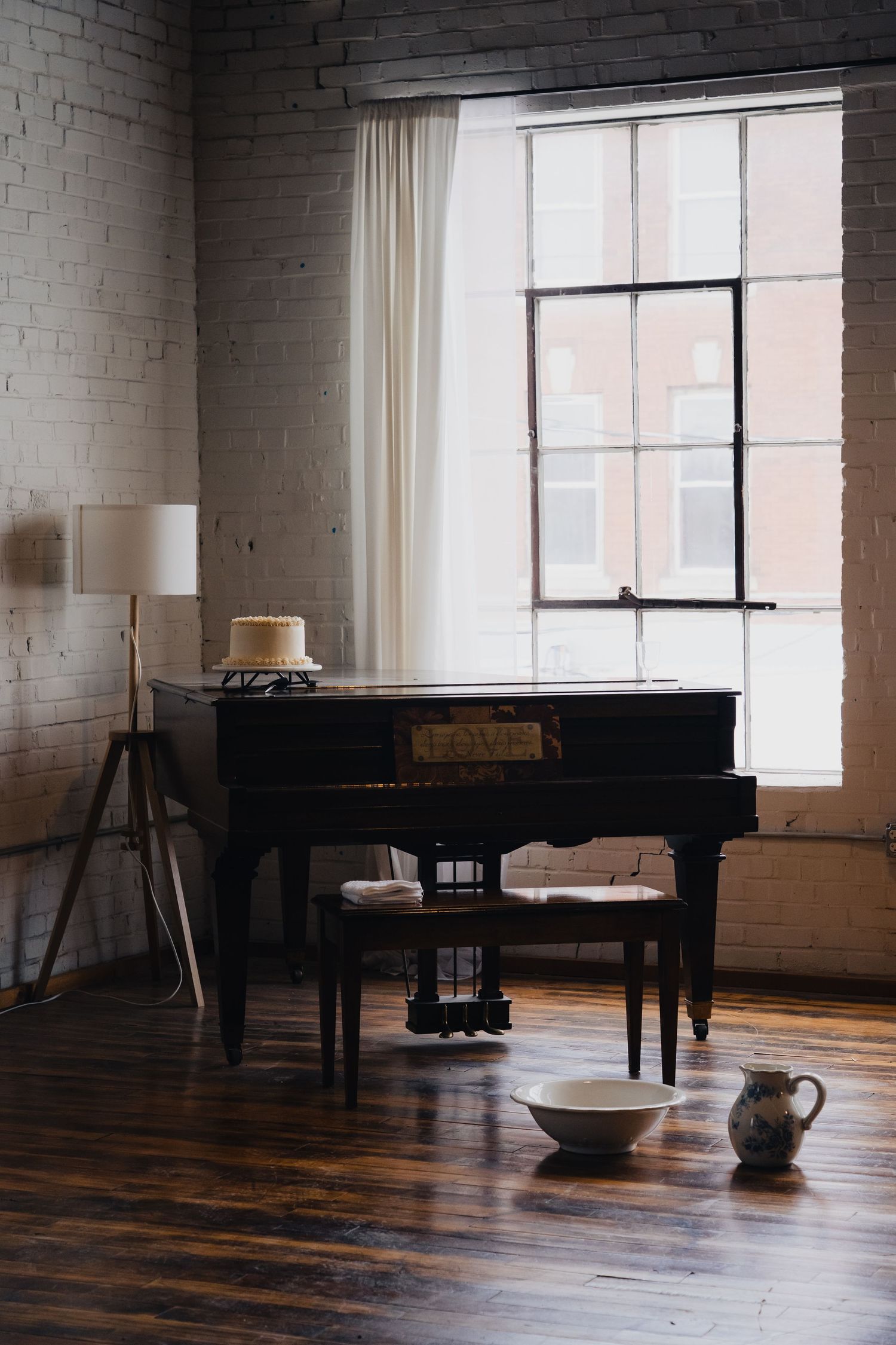 A series of grand pianos arranged in a spacious loft studio with white brick walls and hardwood flooring.